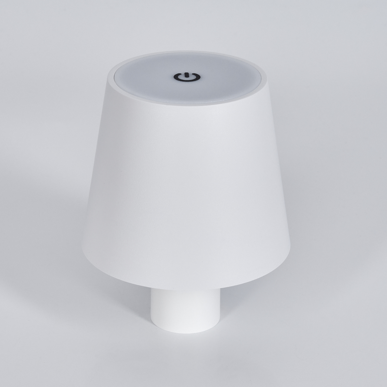 Weiße Lampe mit Ein-/Aus-Symbol auf dem oberen Knopf, auf grauem Hintergrund.