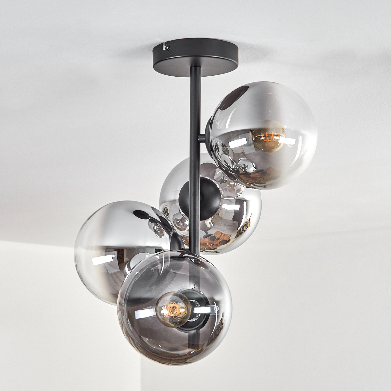 Eine Deckenleuchte mit vier rauchglas-Kugeln und sichtbaren Glühbirnen.