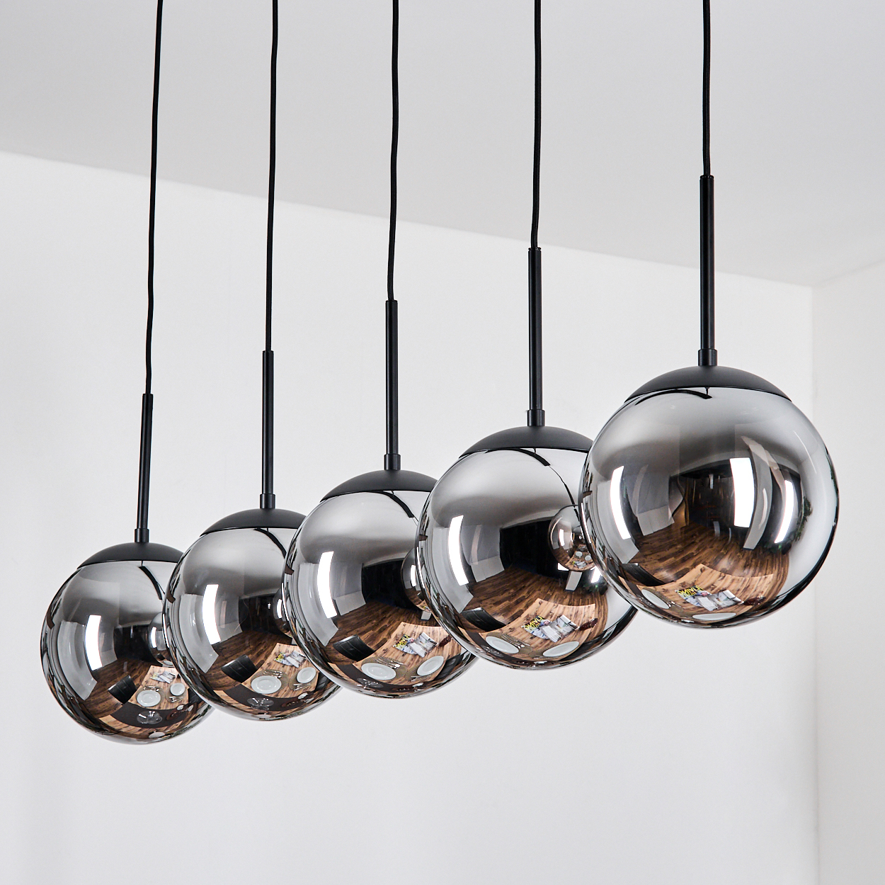 Fünf kugelförmige Pendelleuchten mit Rauchglas und schwarzen Akzenten.