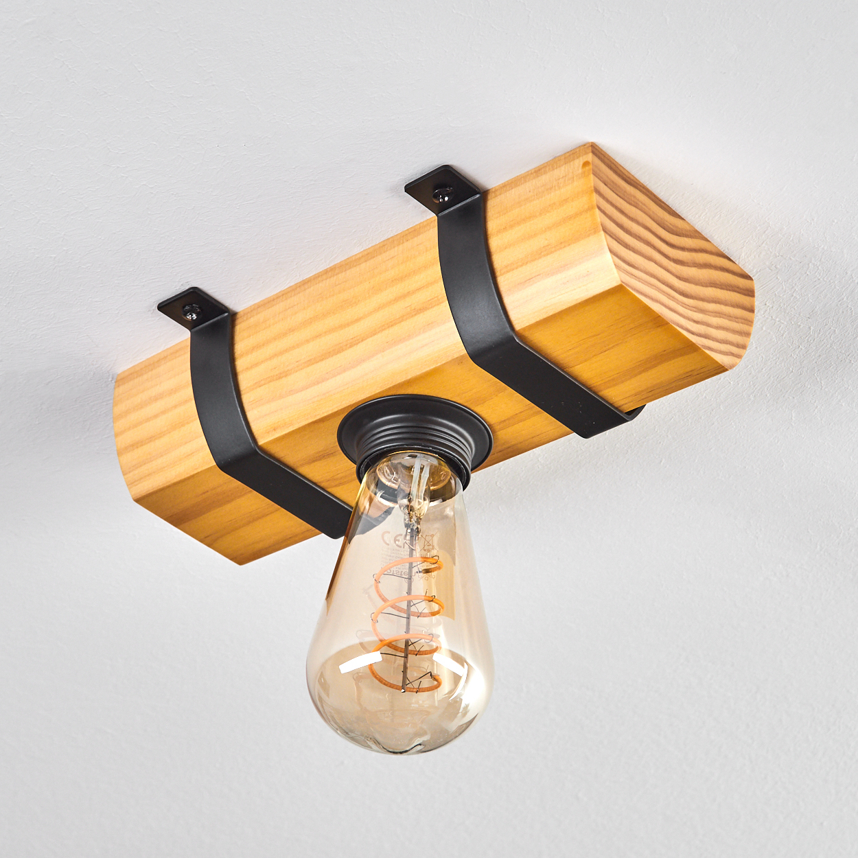 Holzbalkenleuchte mit Edison-Glühbirne und schwarzen Halterungen an einer weißen Decke.