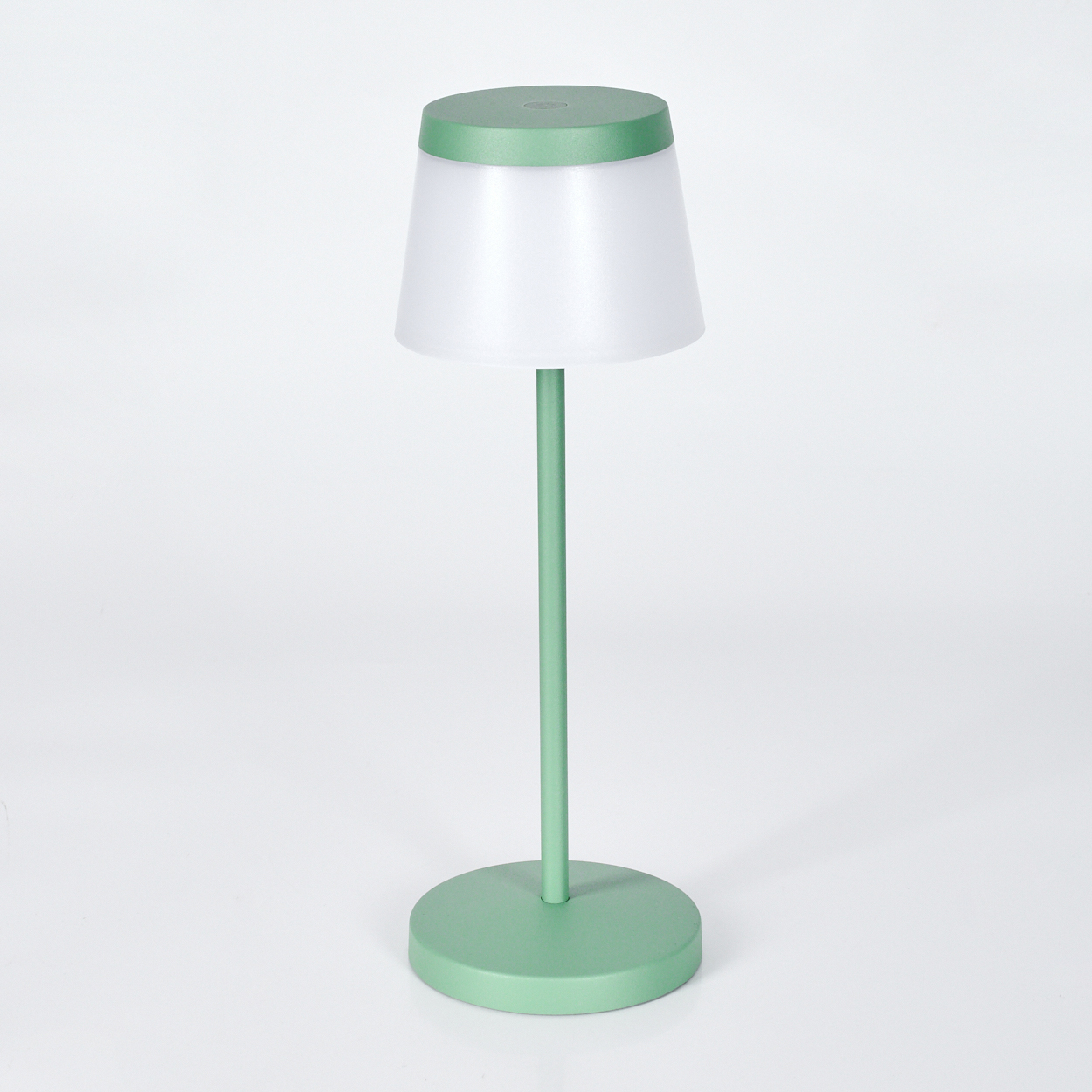 Eine grüne Tischlampe mit weißem Schirm steht auf einem runden Sockel.