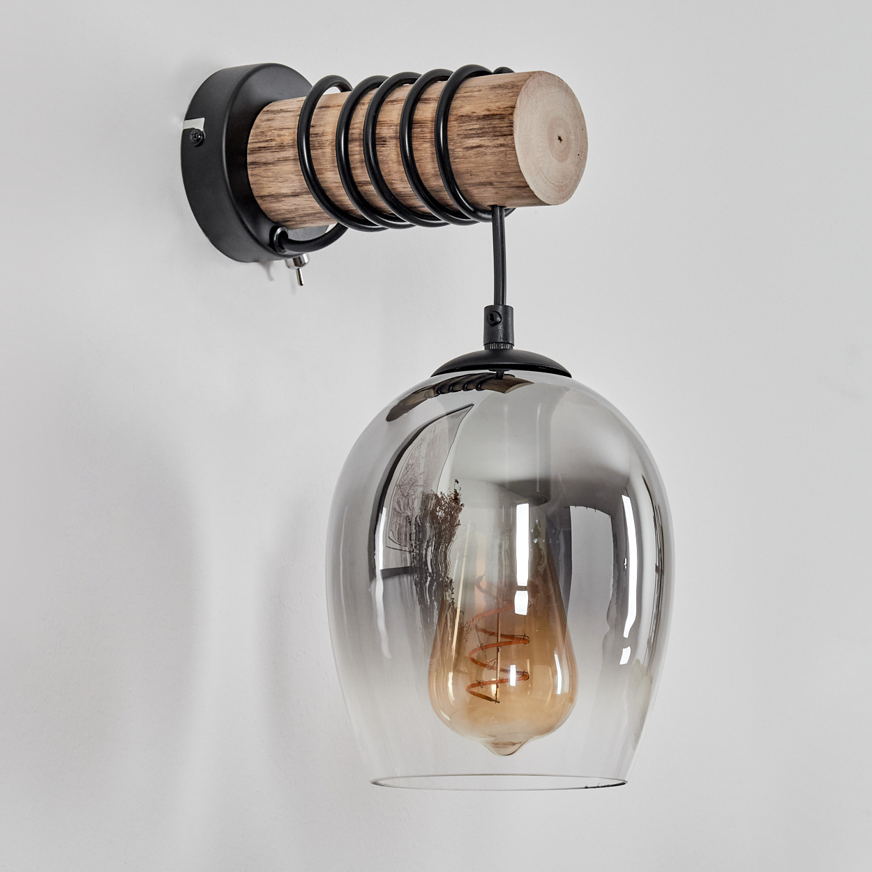 Eine Wandleuchte mit Holzarm, schwarzen Spiralen und einem Rauchglaslampenschirm mit Glühbirne.