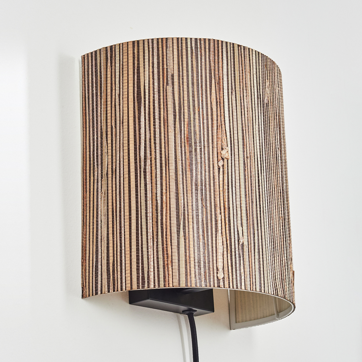Eine Wandleuchte mit einem zylindrischen Lampenschirm aus Holzstreifen.