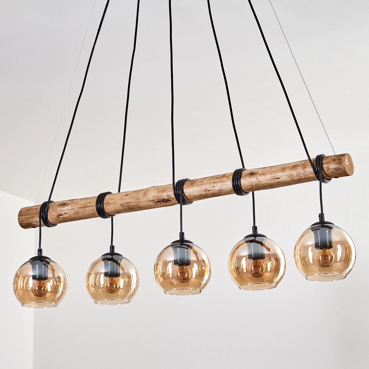 Ein Hängelampen-Kronleuchter mit einem Holzstamm und bernsteinfarbenen Glaskugeln.