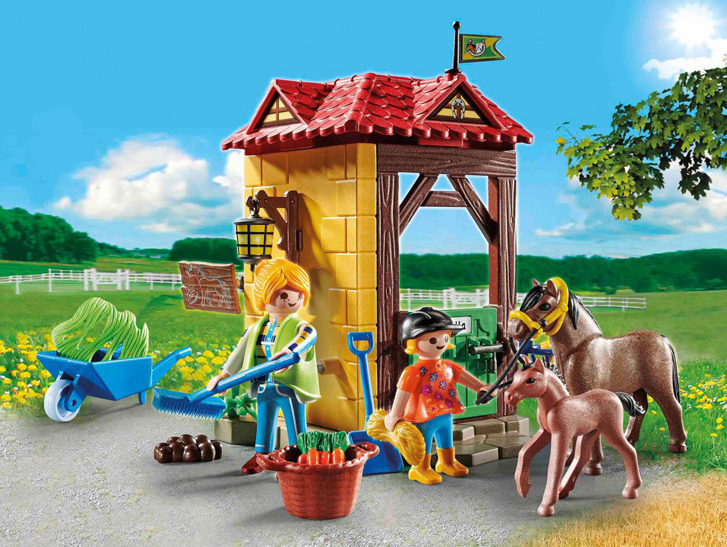 Deux figurines Playmobil avec des chevaux et une charrette devant une étable dans une ferme.