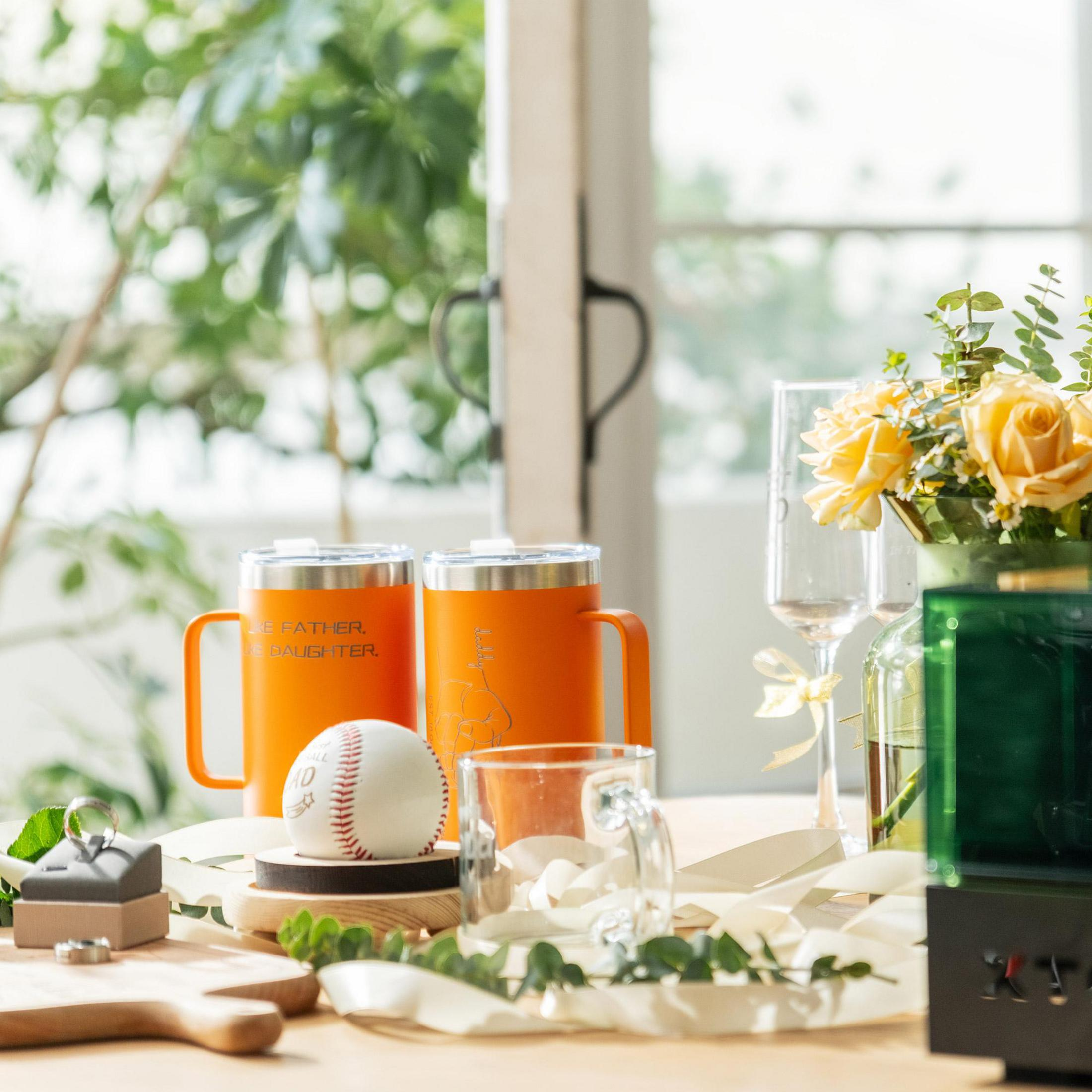 Zwei orangefarbene Becher, Baseball, Ringe, Gläser und Blumen.
