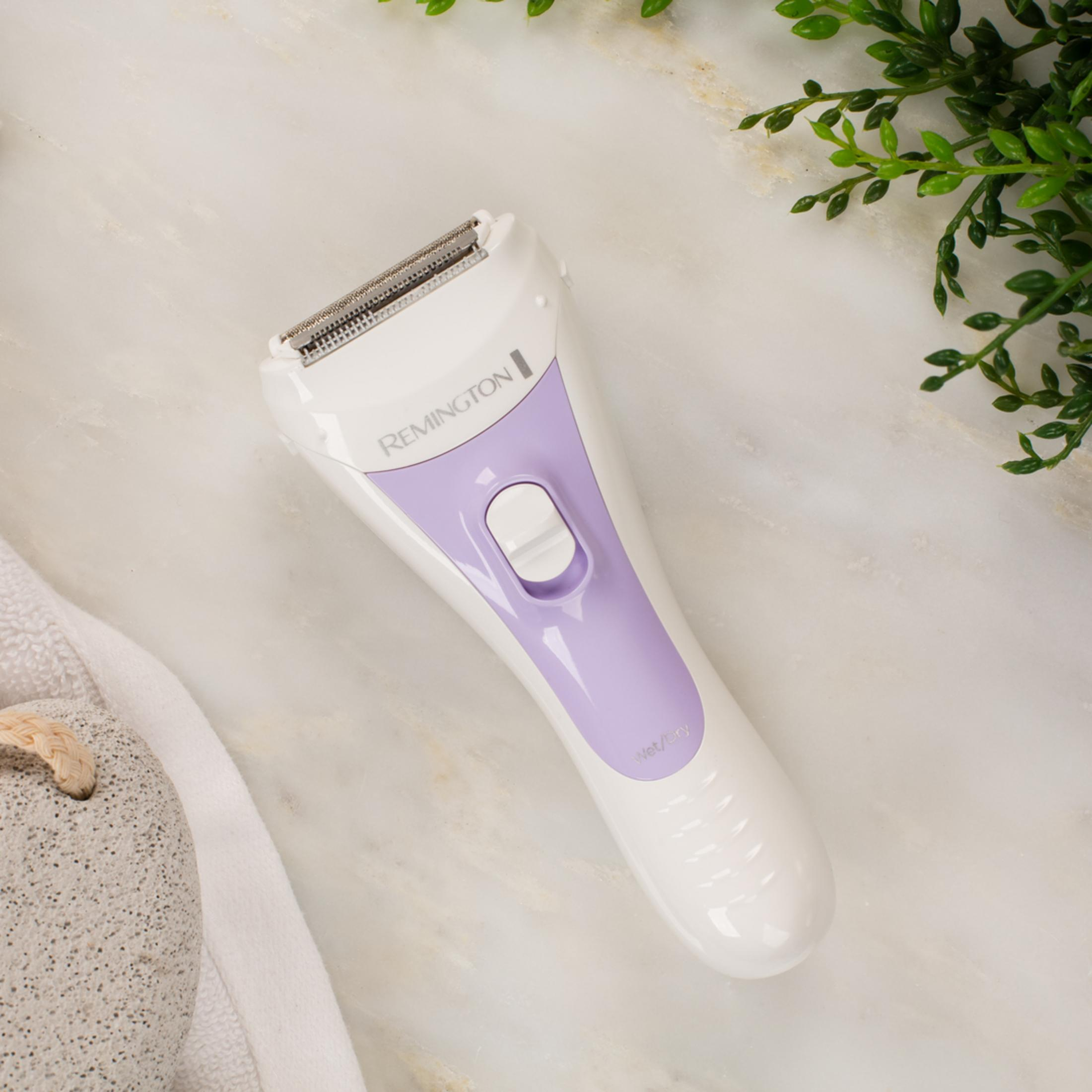 Un rasoio Remington bianco con accenti viola riposa sul marmo.