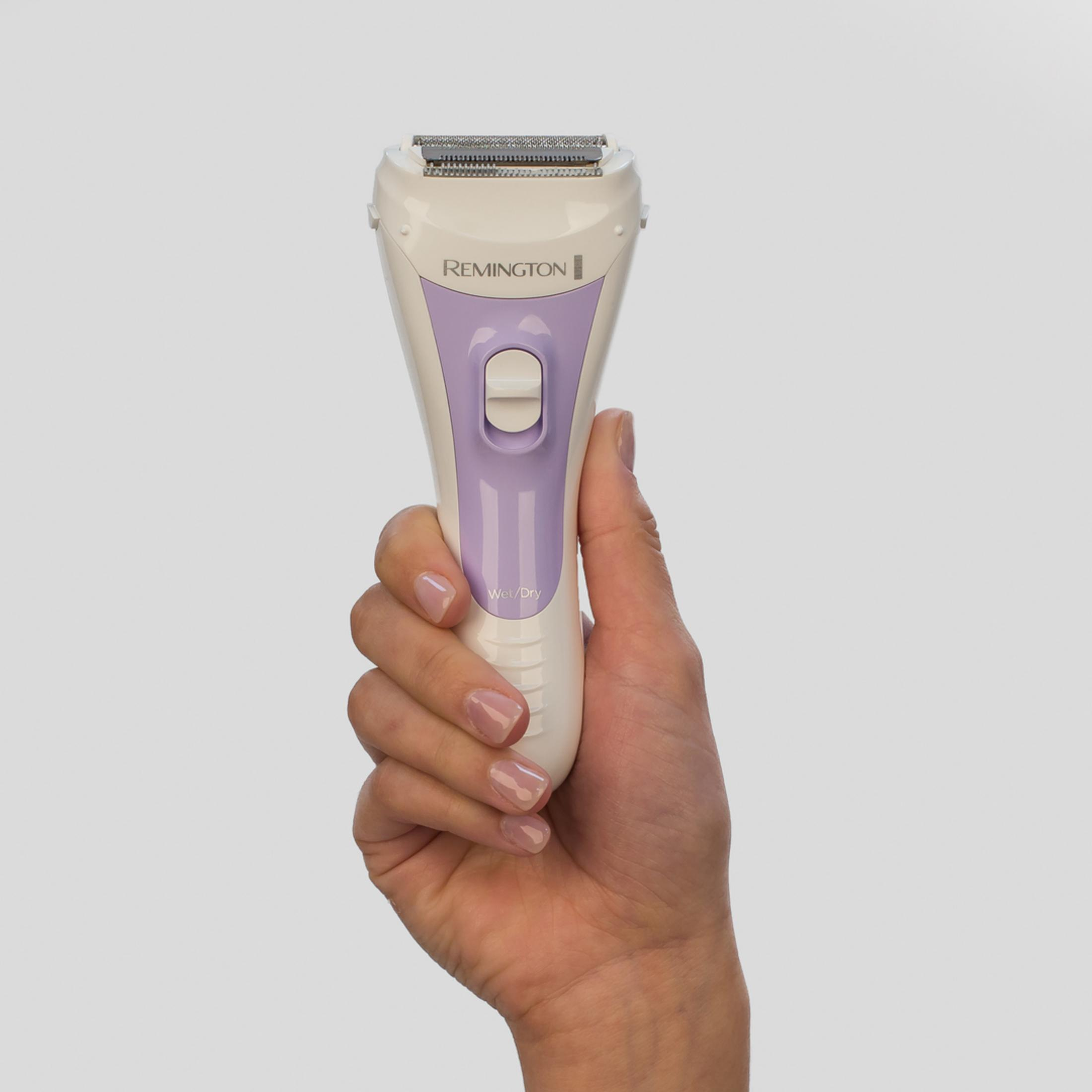 Una mano tiene un rasoio elettrico Remington bianco e viola.