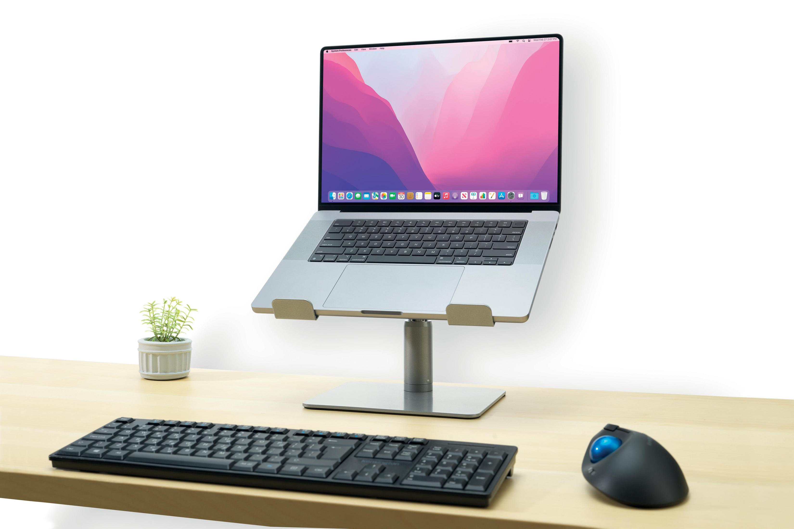Een laptop op een standaard, met toetsenbord en muis in de buurt.