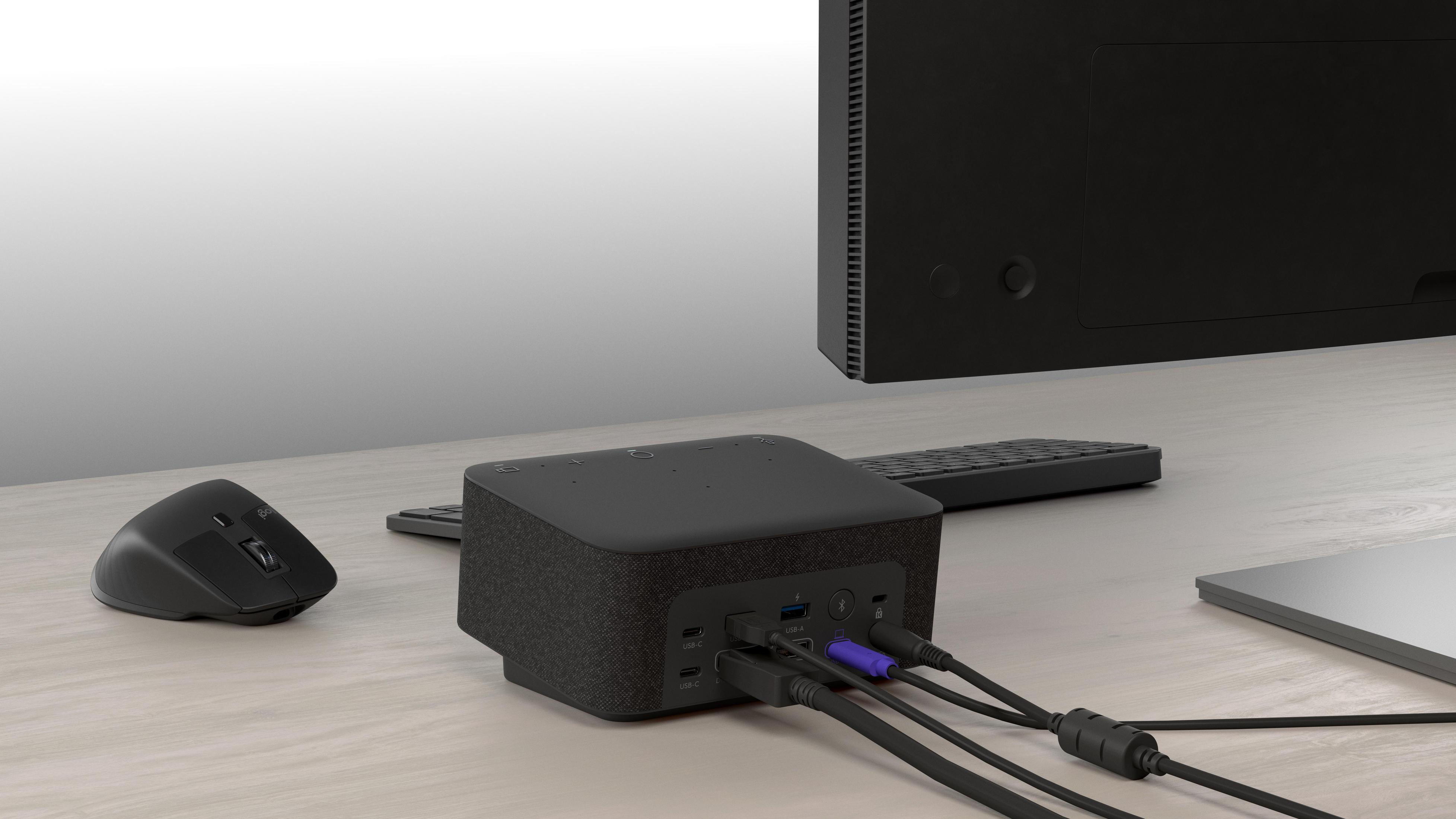 Un concentrador de computadora negro con cables, mouse y teclado conectados en un escritorio.