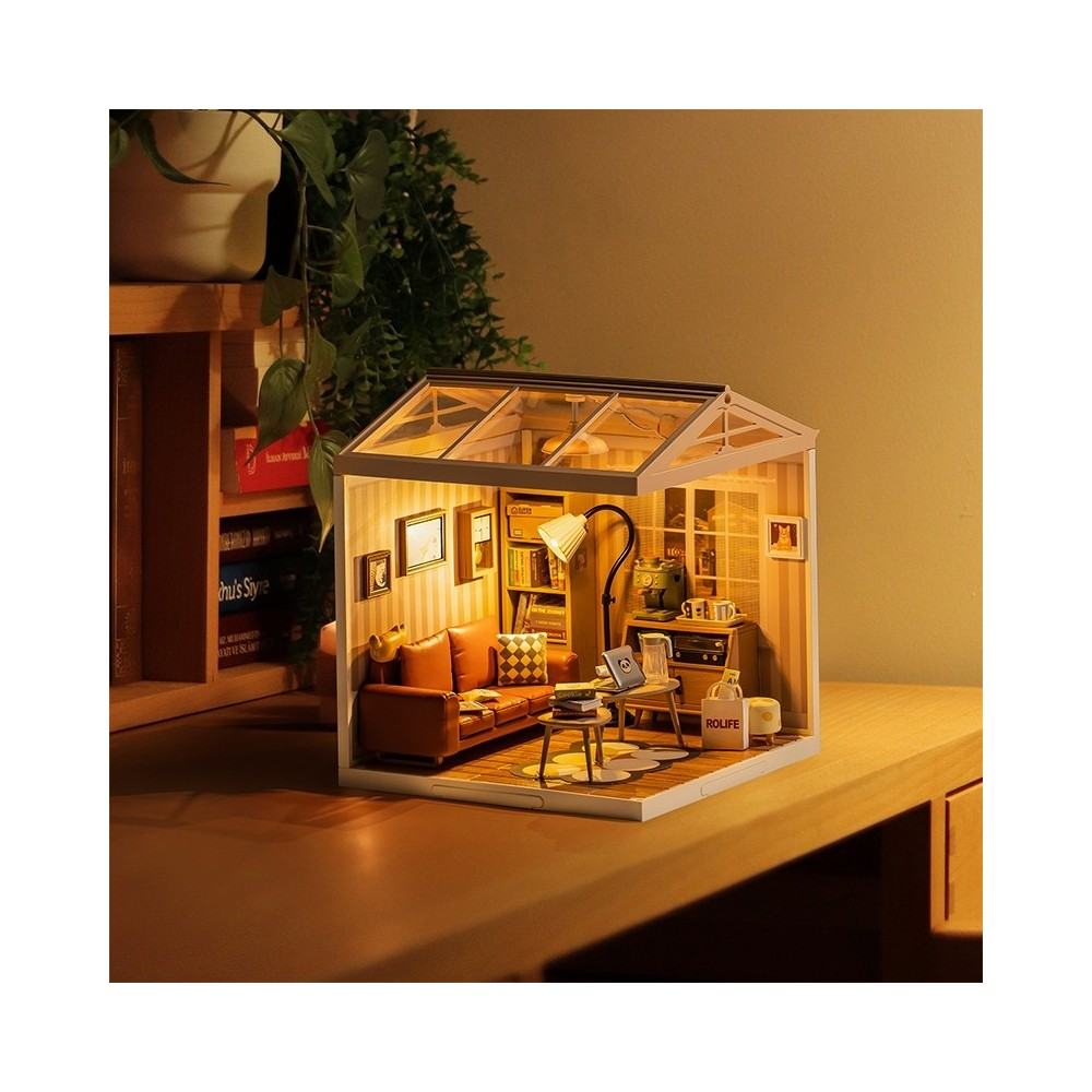 Miniatur-Wohnzimmer mit braunem Sofa, Büchern, Lampe und Glasdach.