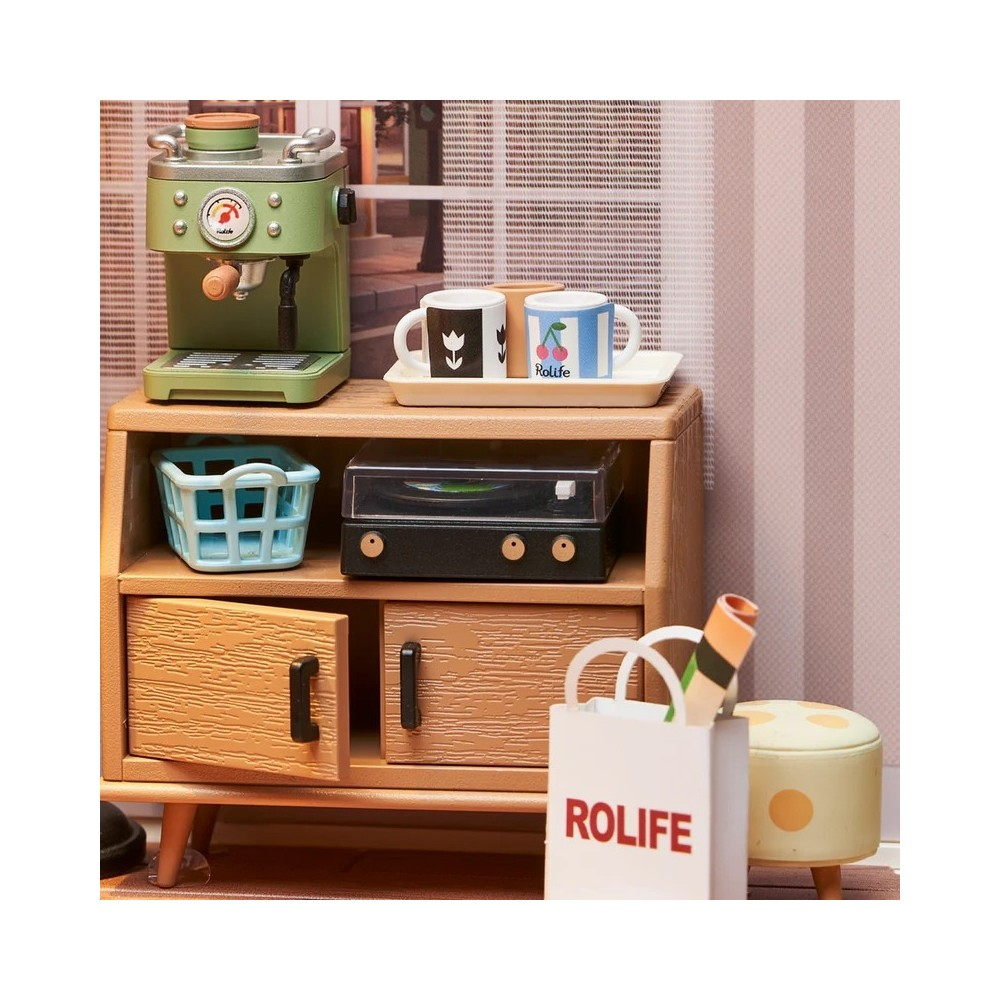 Miniatur-Kaffeemaschine, Plattenspieler, Tassen und ein Beutel auf einem Holzschrank.