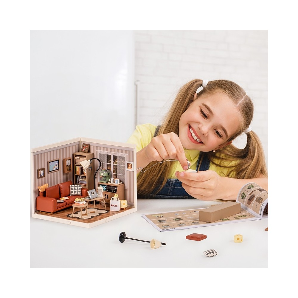 Ein Mädchen baut ein Miniaturwohnzimmer mit Möbeln und Dekorationen.