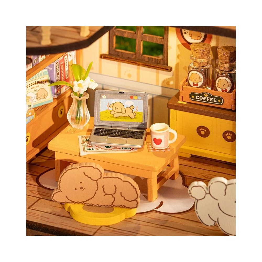 Miniatur-Schreibtisch mit Laptop, Tasse, Blumen und Hundedekoration.