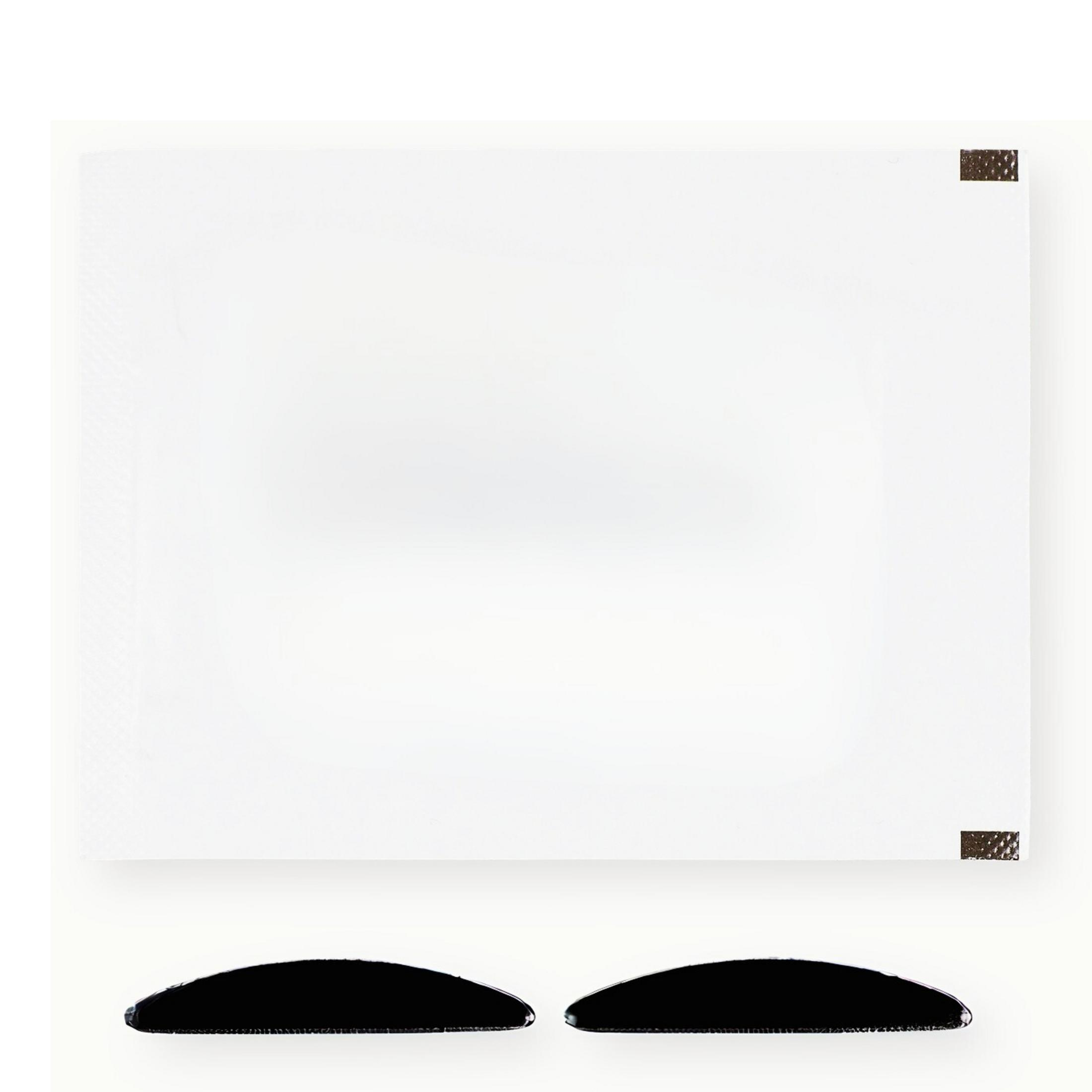 Ein weißes Blatt Papier mit dunkelbraunen Ecken und zwei schwarzen, gebogenen Objekten darunter.