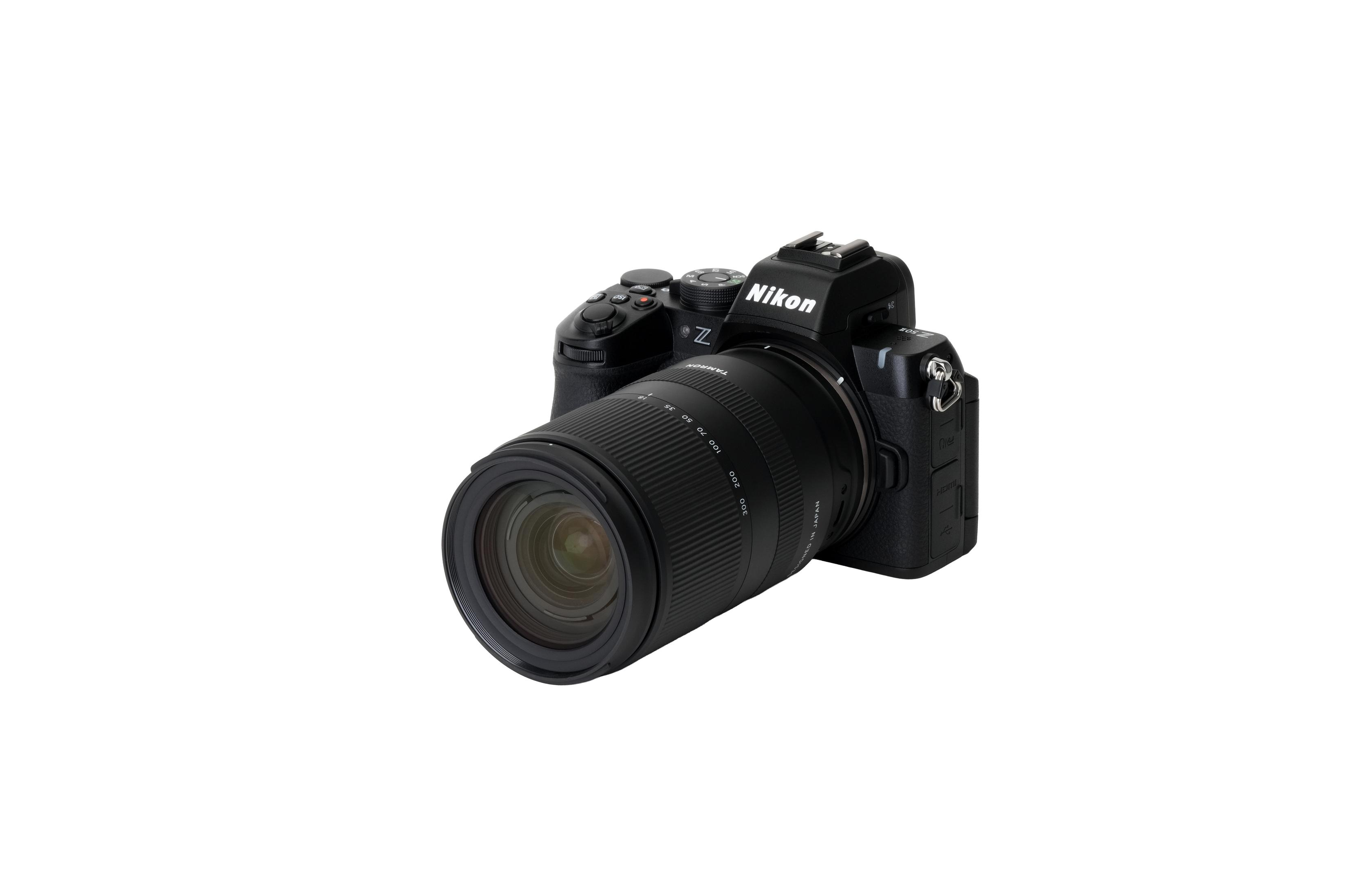Una fotocamera Nikon Z nera con obiettivo Tamron è mostrata su sfondo bianco.