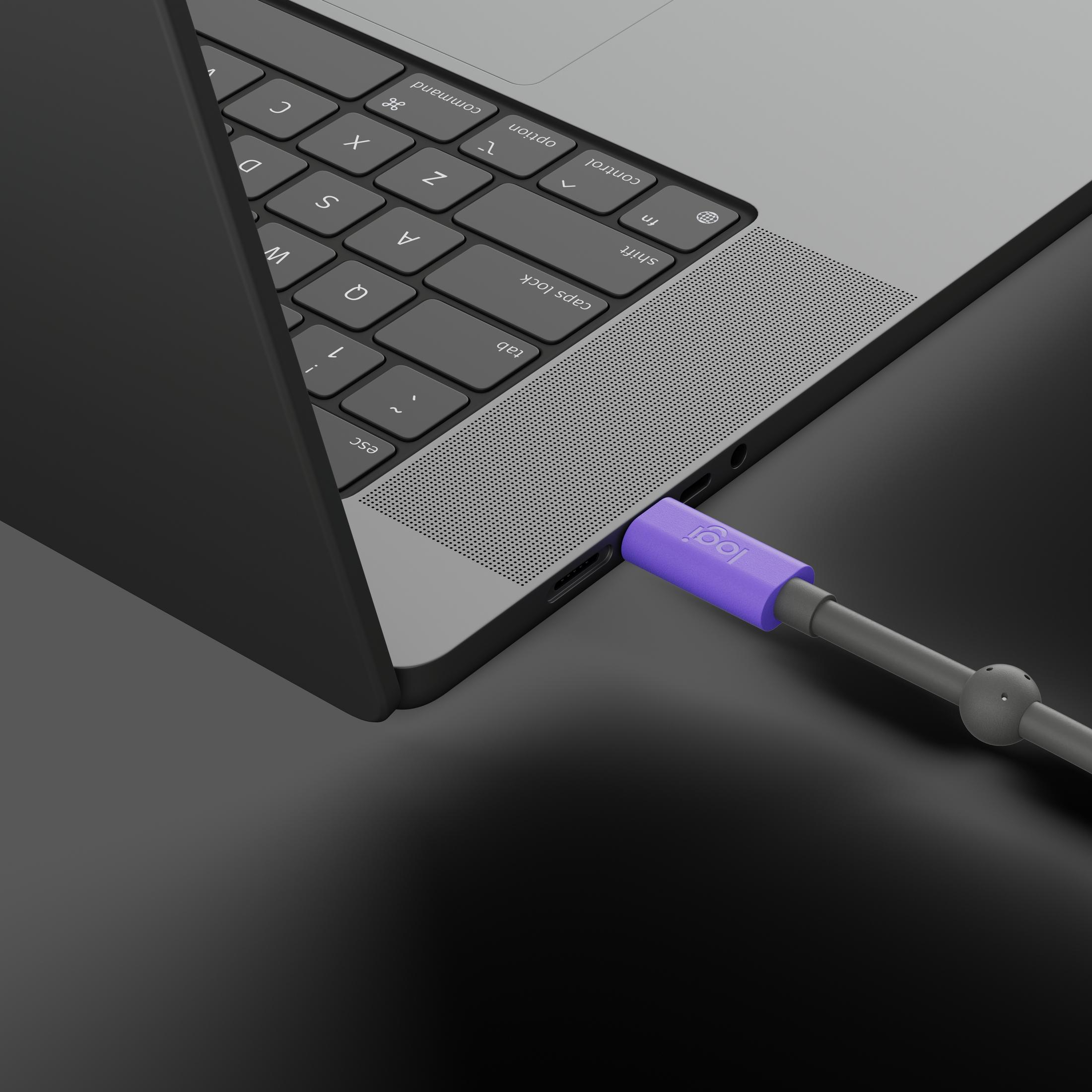 Un dongle Logi viola è collegato a un laptop su una superficie scura.