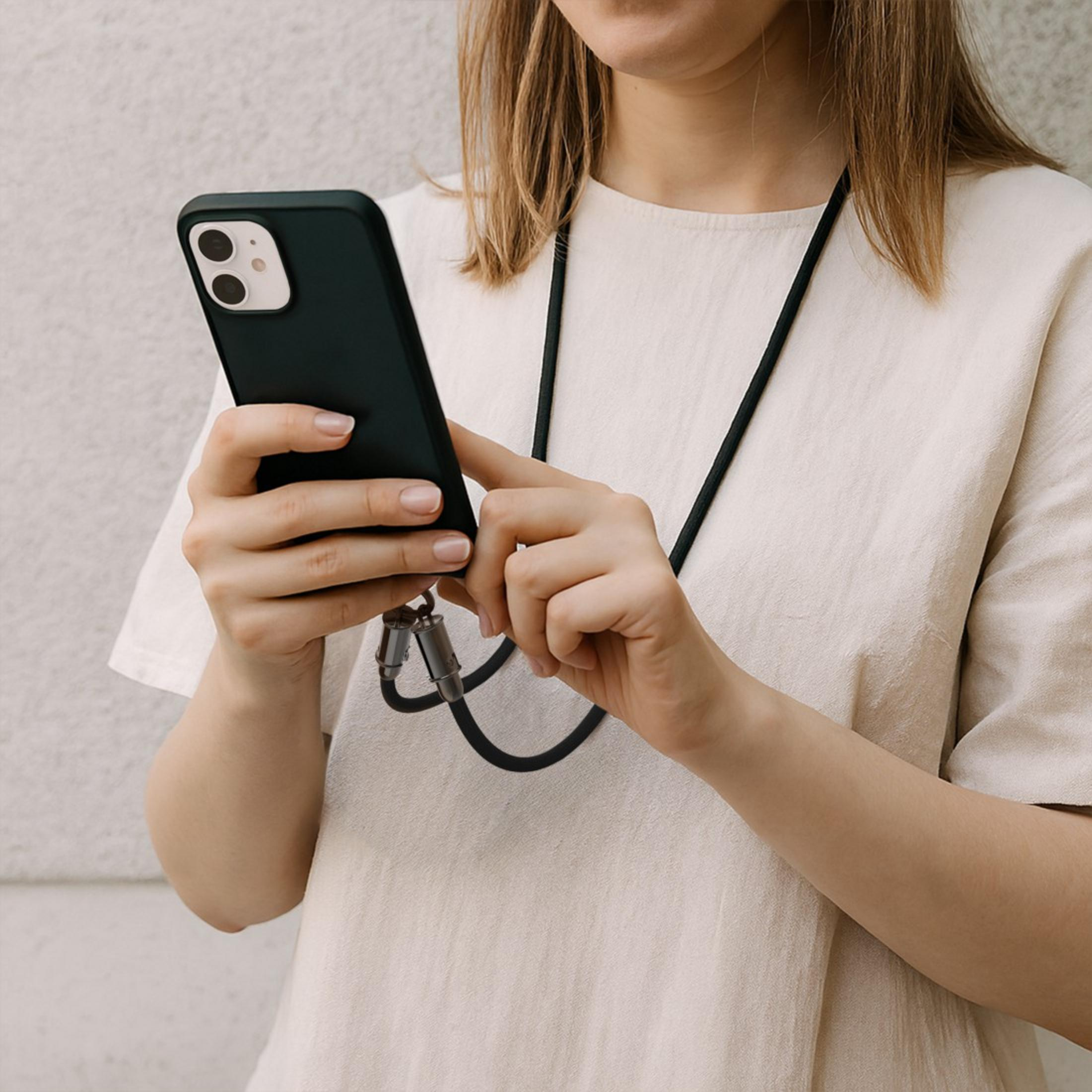 Una persona tiene uno smartphone nero con un laccetto al collo.
