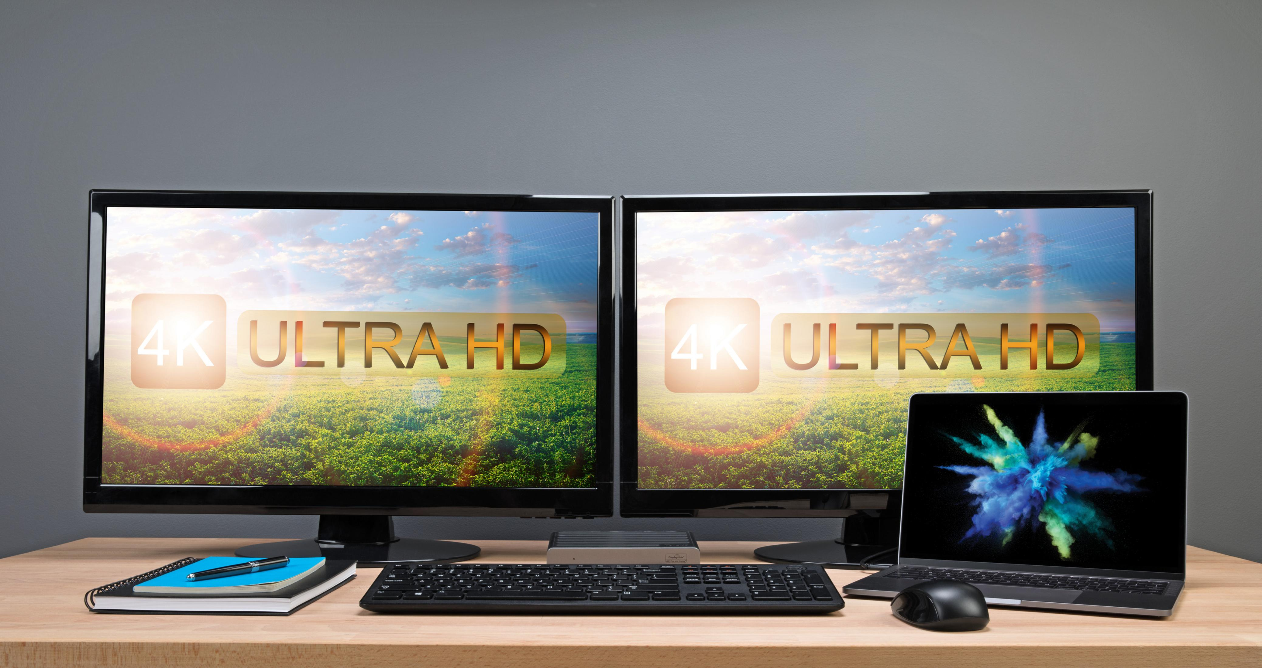 Due monitor 4K Ultra HD e un laptop su una scrivania.