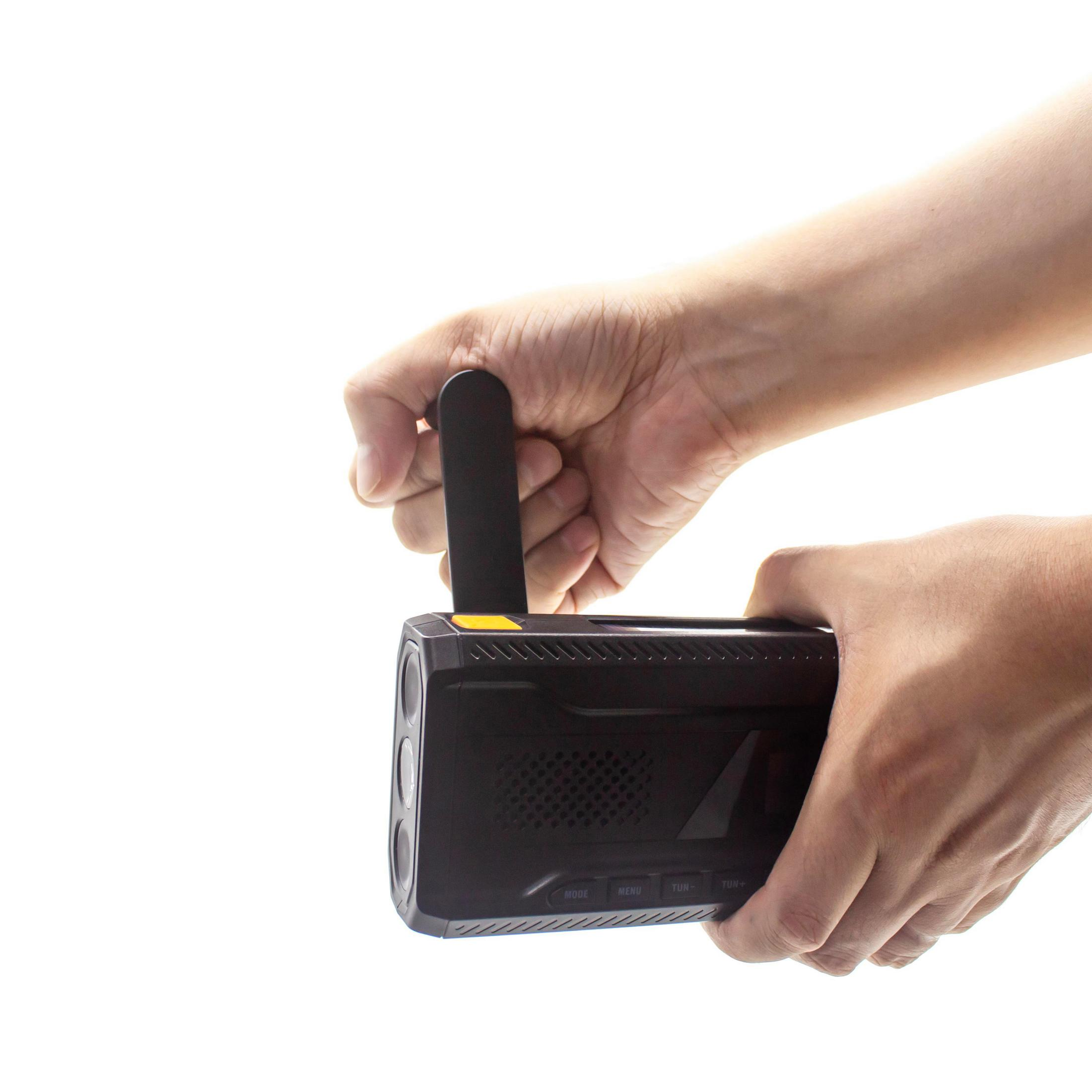 A hand holds a black device with a pull-up antenna.