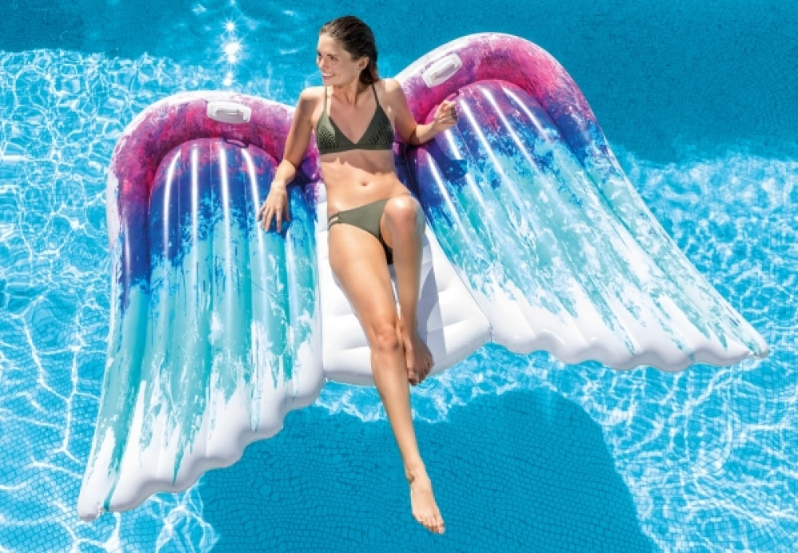 Frau auf aufblasbarem Engelsflügel-Schwimmring im Pool mit blauem Wasser.