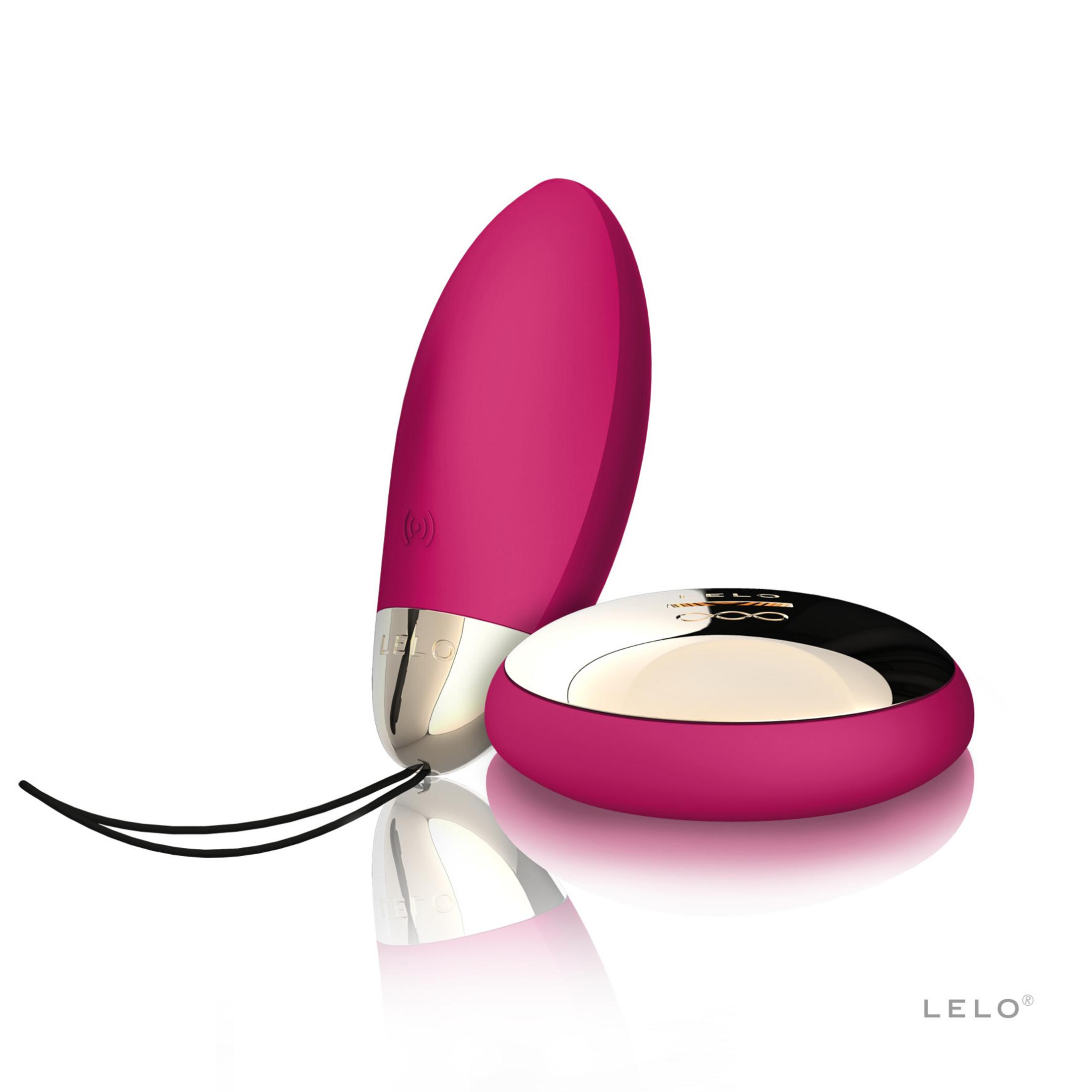 Un vibrador rosa con base plateada junto a un cargador redondo.