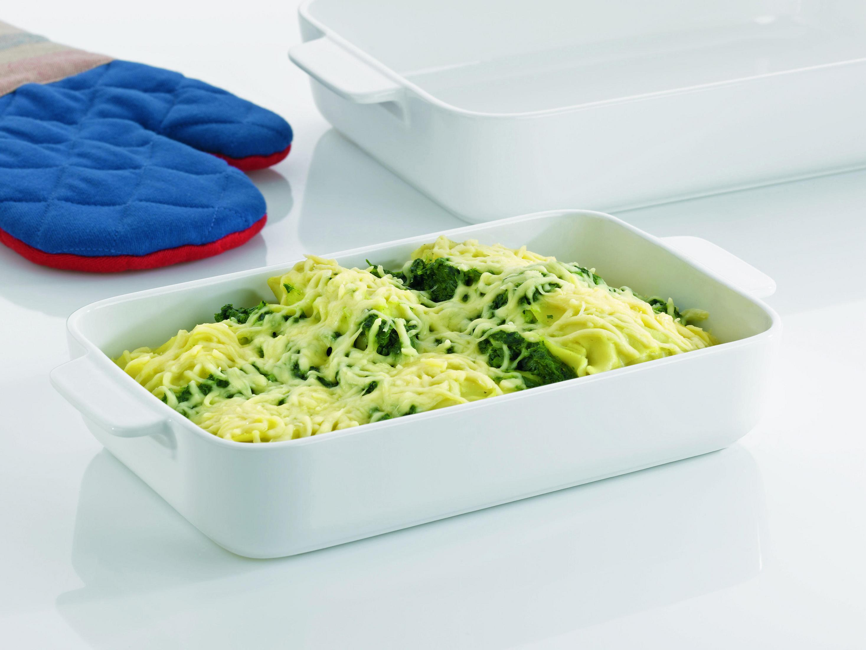 Auflaufform mit Nudeln, Brokkoli und Käse, daneben ein Topflappen.