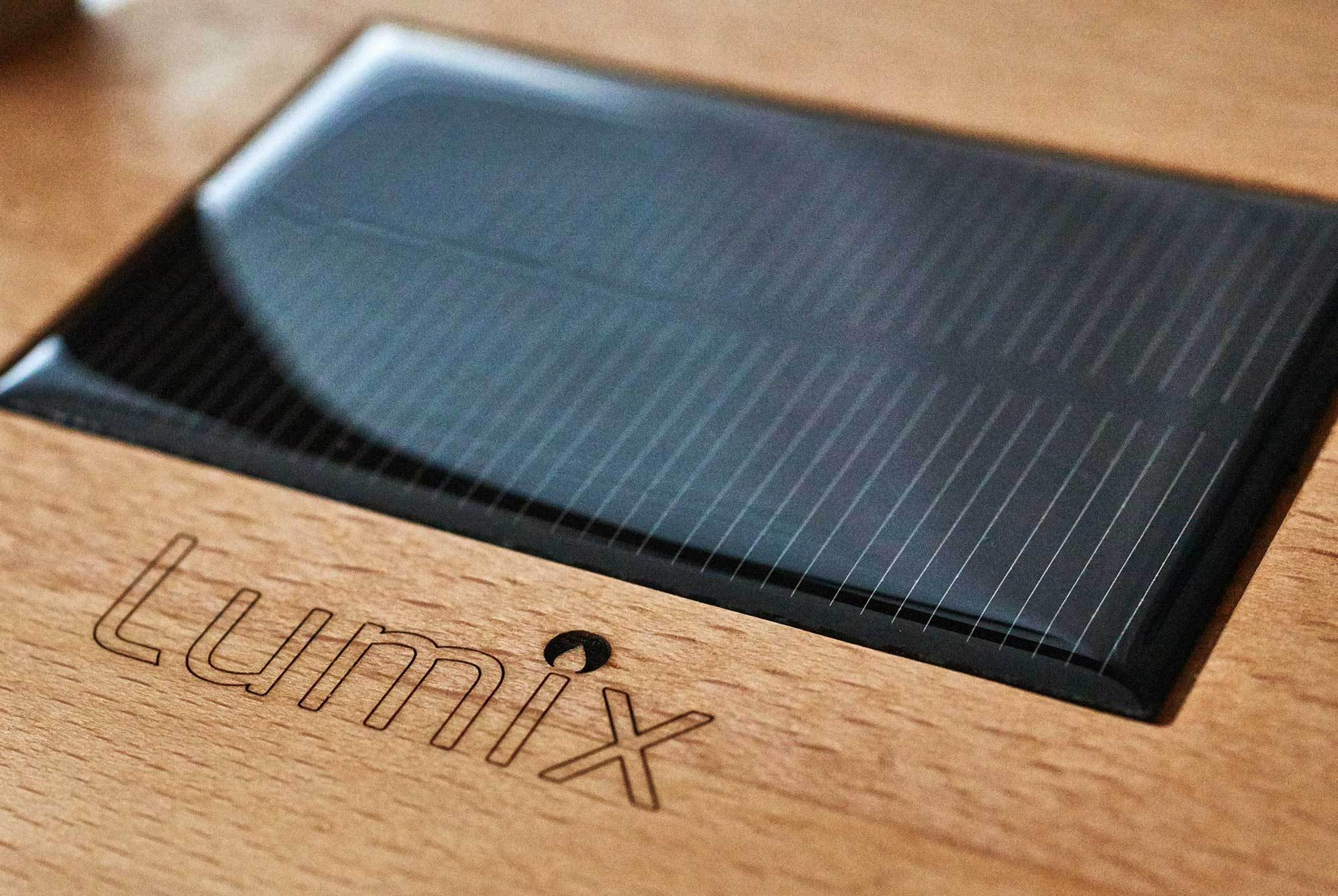 Nahaufnahme eines schwarzen Solarmoduls mit Lumix-Logo auf Holz.