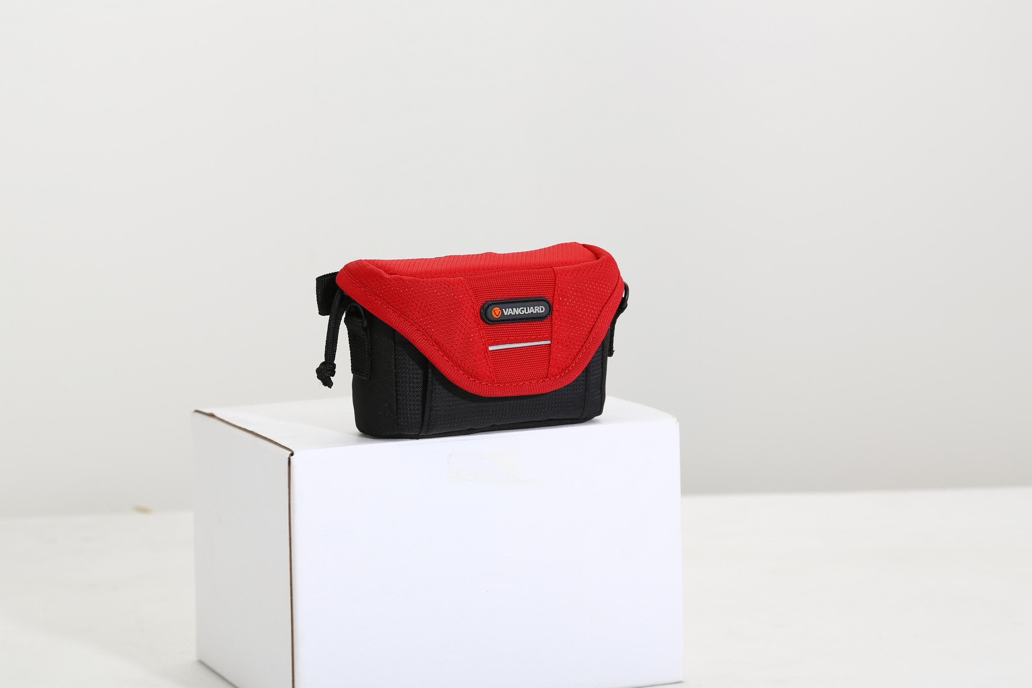 Una bolsa de cámara Vanguard roja y negra sobre un cubo blanco.