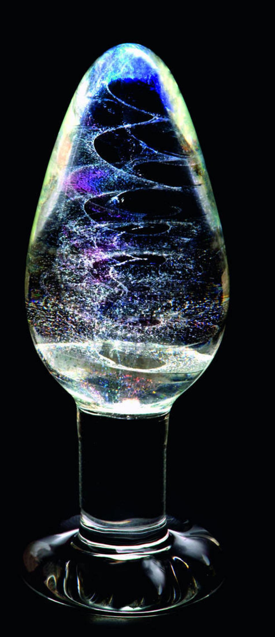 Ein Glasobjekt mit wirbelnden Farben und Glitzerpartikeln auf schwarzem Hintergrund.