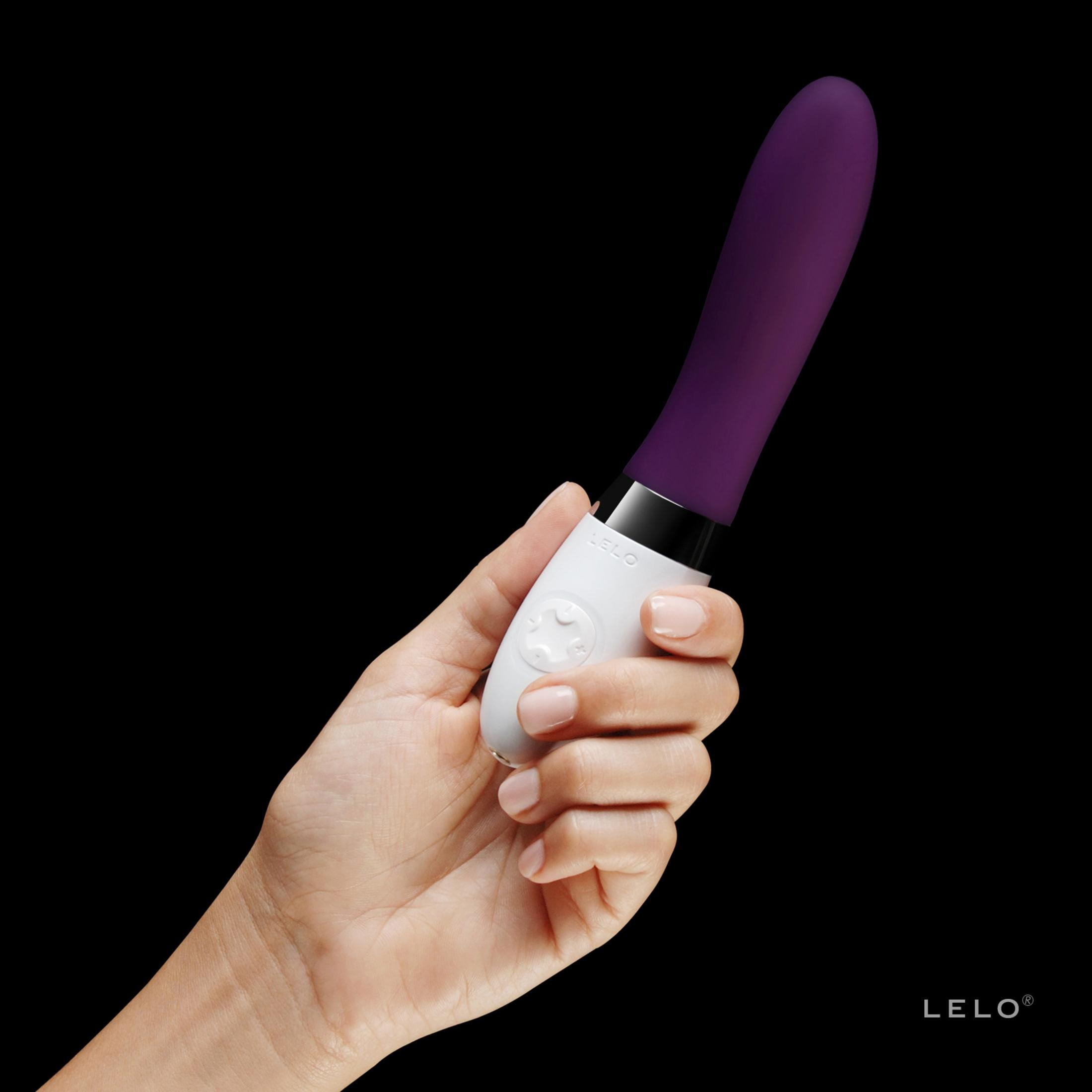Eine Hand hält einen weißen Vibrator mit lila Spitze.