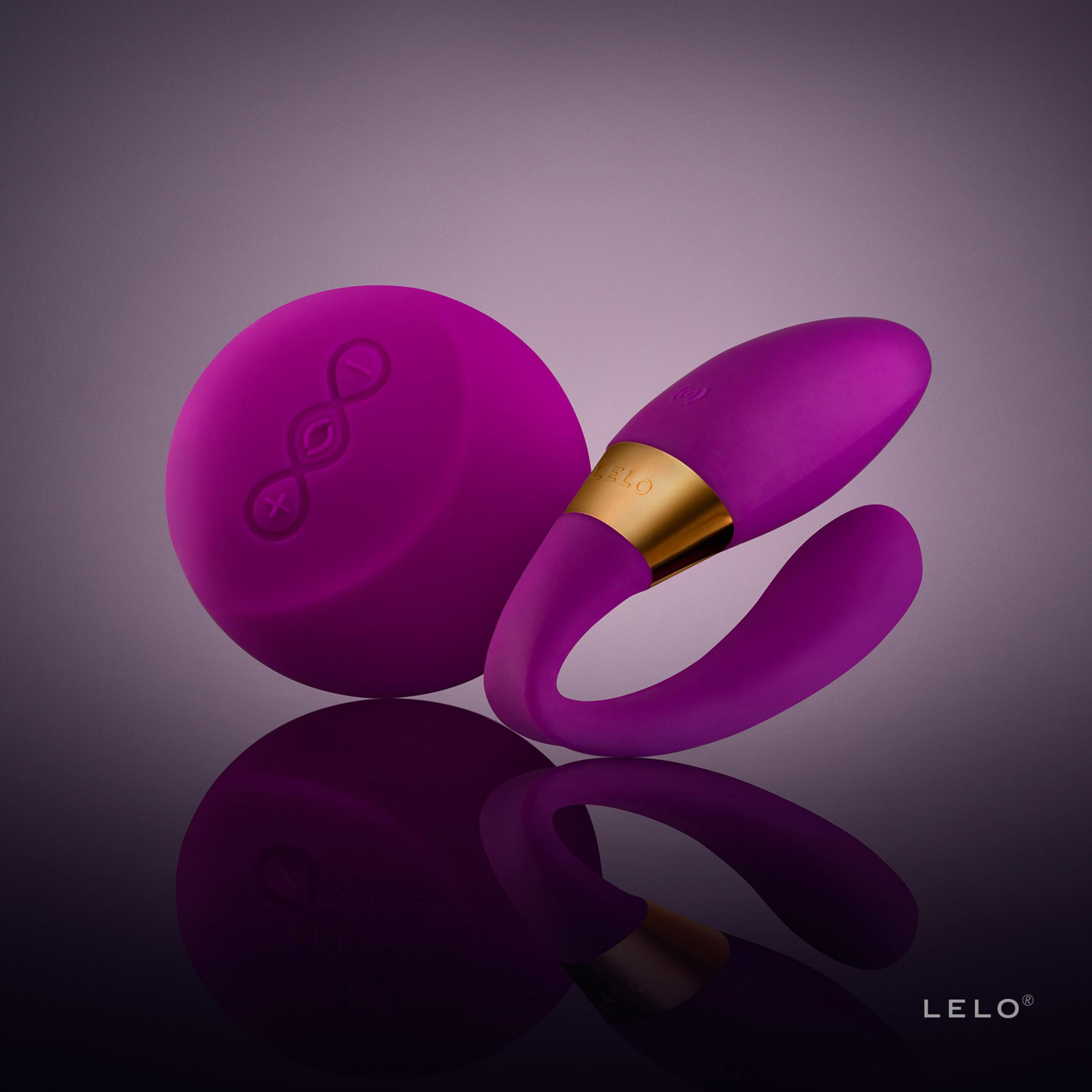 Un vibrador morado con banda dorada junto a una unidad de carga redonda.