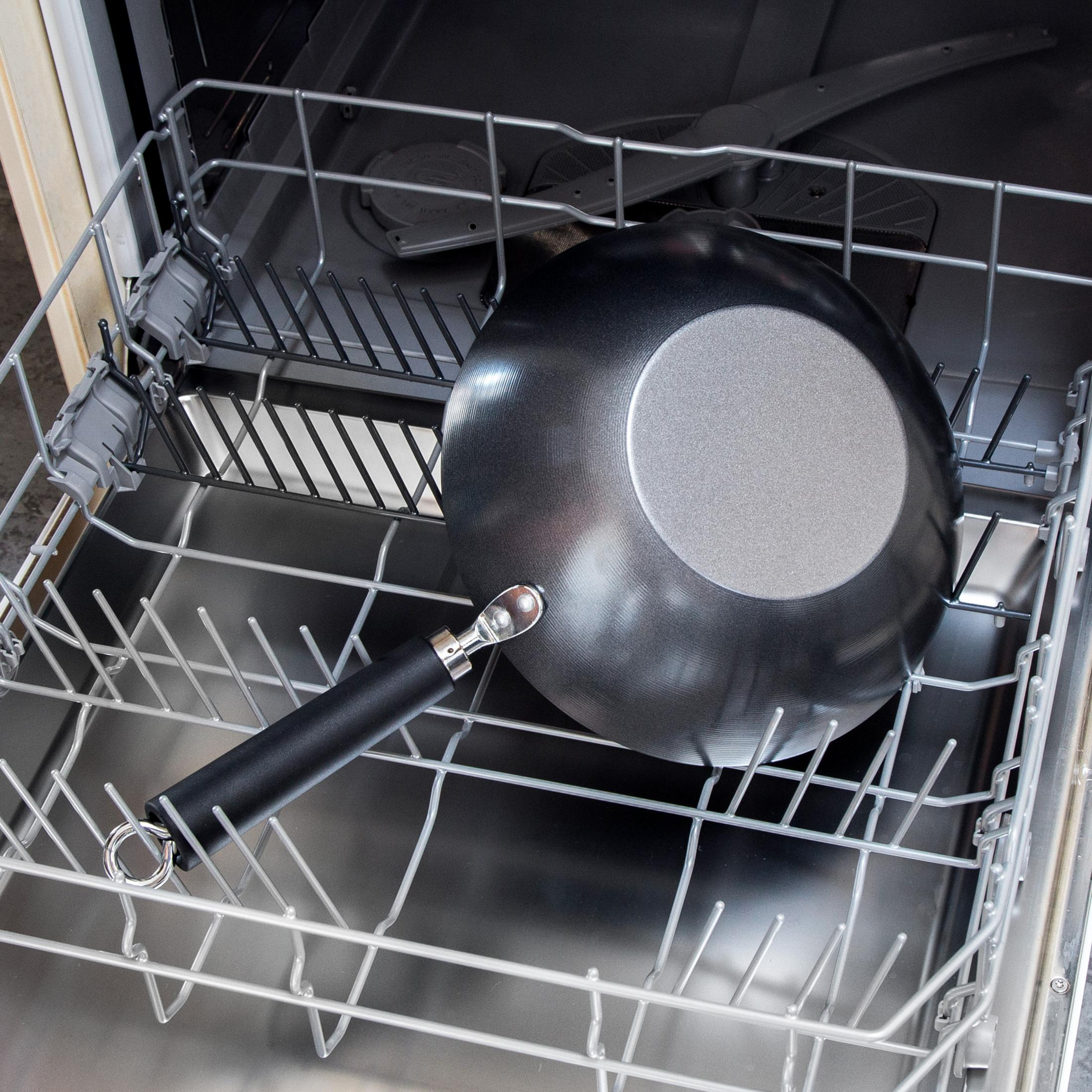 Un wok noir avec un manche repose dans un lave-vaisselle ouvert.