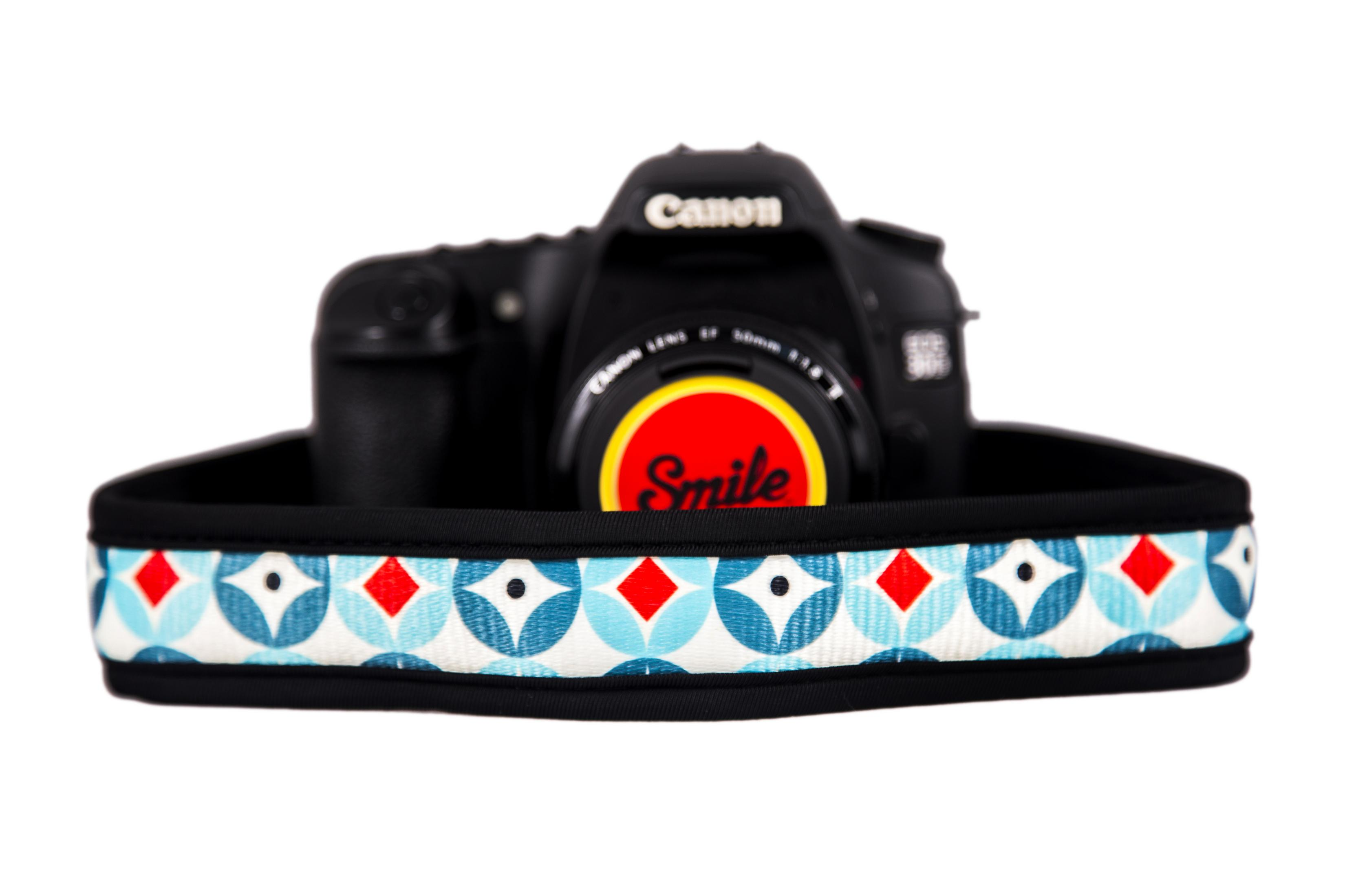 Una fotocamera Canon nera con un cinturino colorato a motivi geometrici.