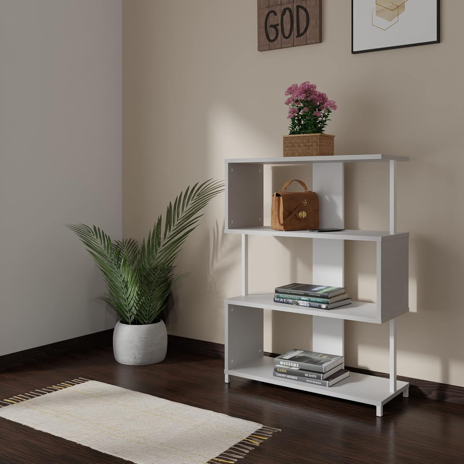 Una estantería blanca asimétrica tiene libros, un bolso y una planta. Hay una alfombra en el suelo.