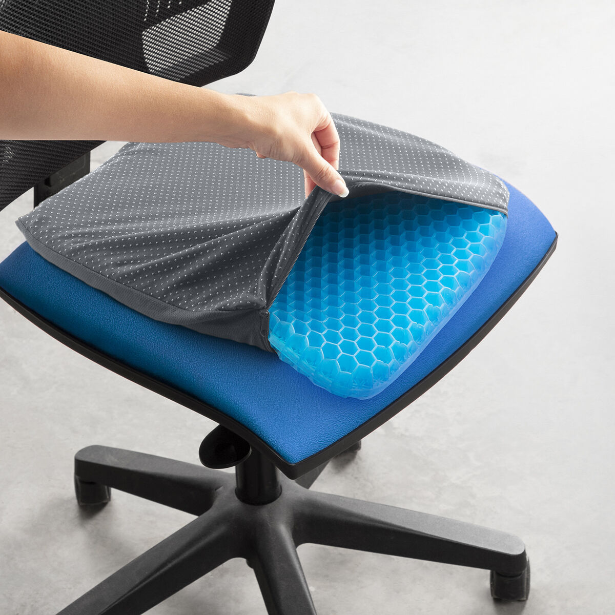 Un braccio solleva una fodera grigia da un cuscino blu su una sedia da ufficio.