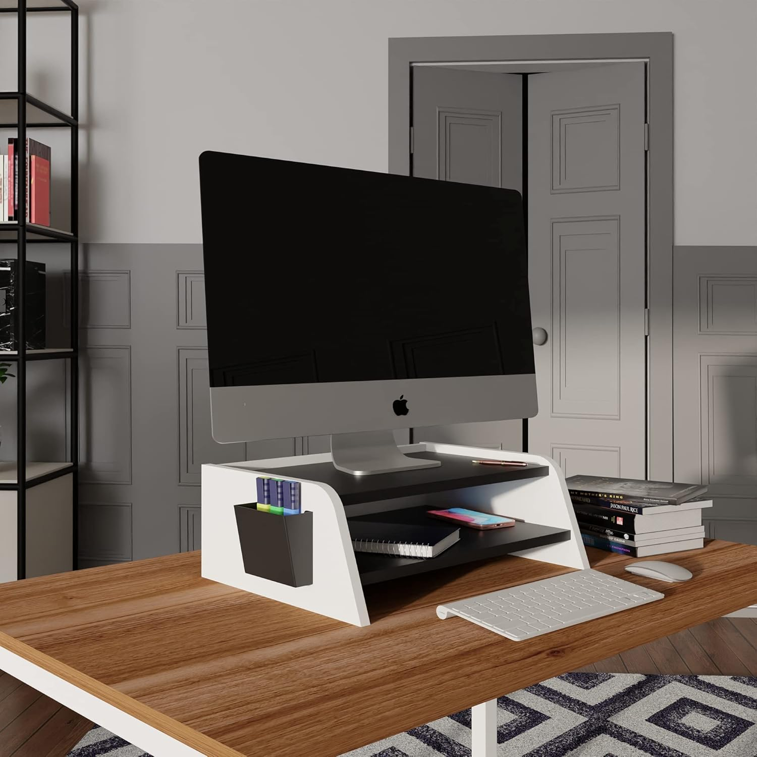 Un escritorio con soporte para monitor, teclado, ratón y libros.