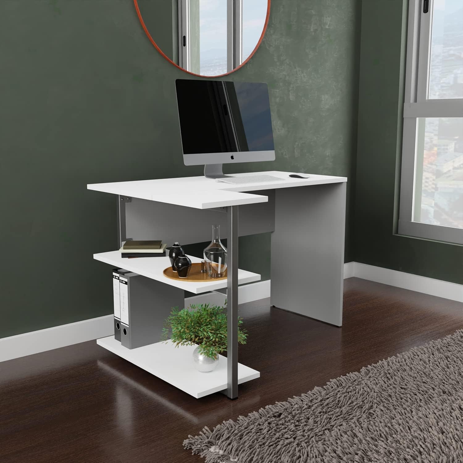 Un escritorio blanco con computadora, estantes con carpetas, planta y decoración en una habitación.
