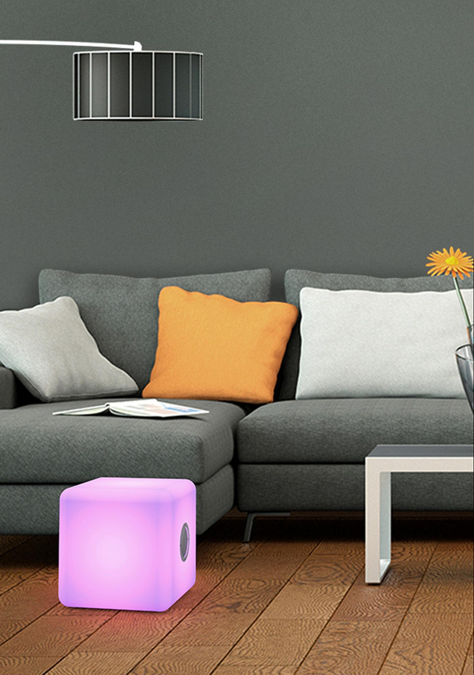 Un cubo viola luminoso è su un pavimento di legno davanti a un divano grigio.