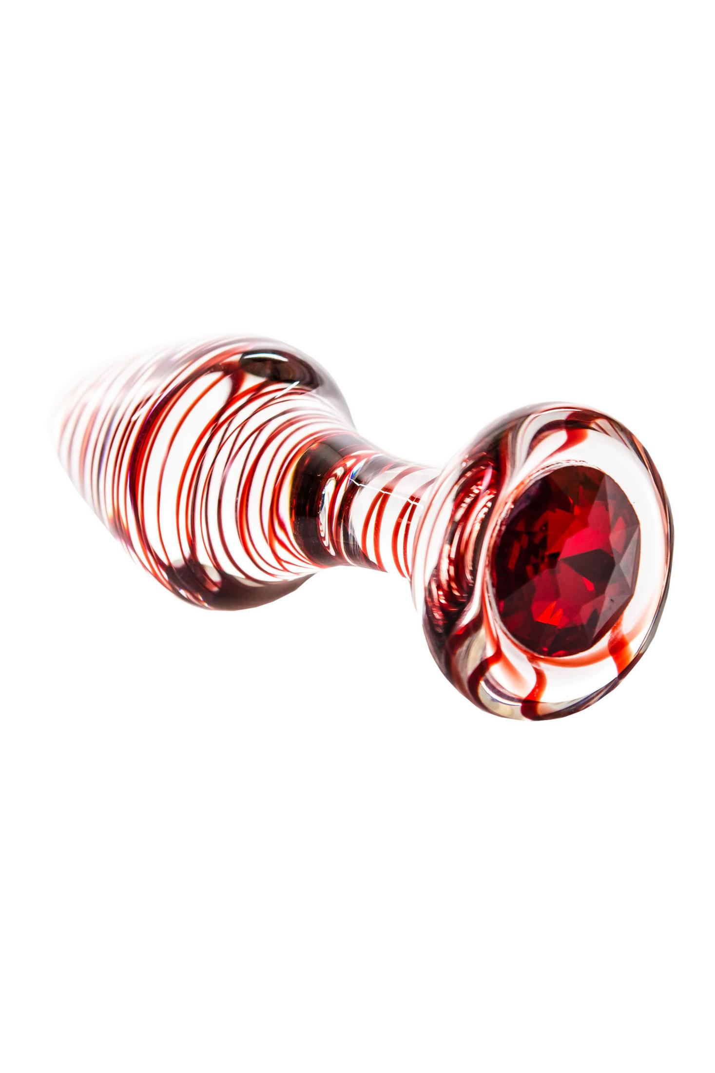 Ein durchsichtiger Glasgegenstand mit roten Spiralen und einem roten Edelstein.