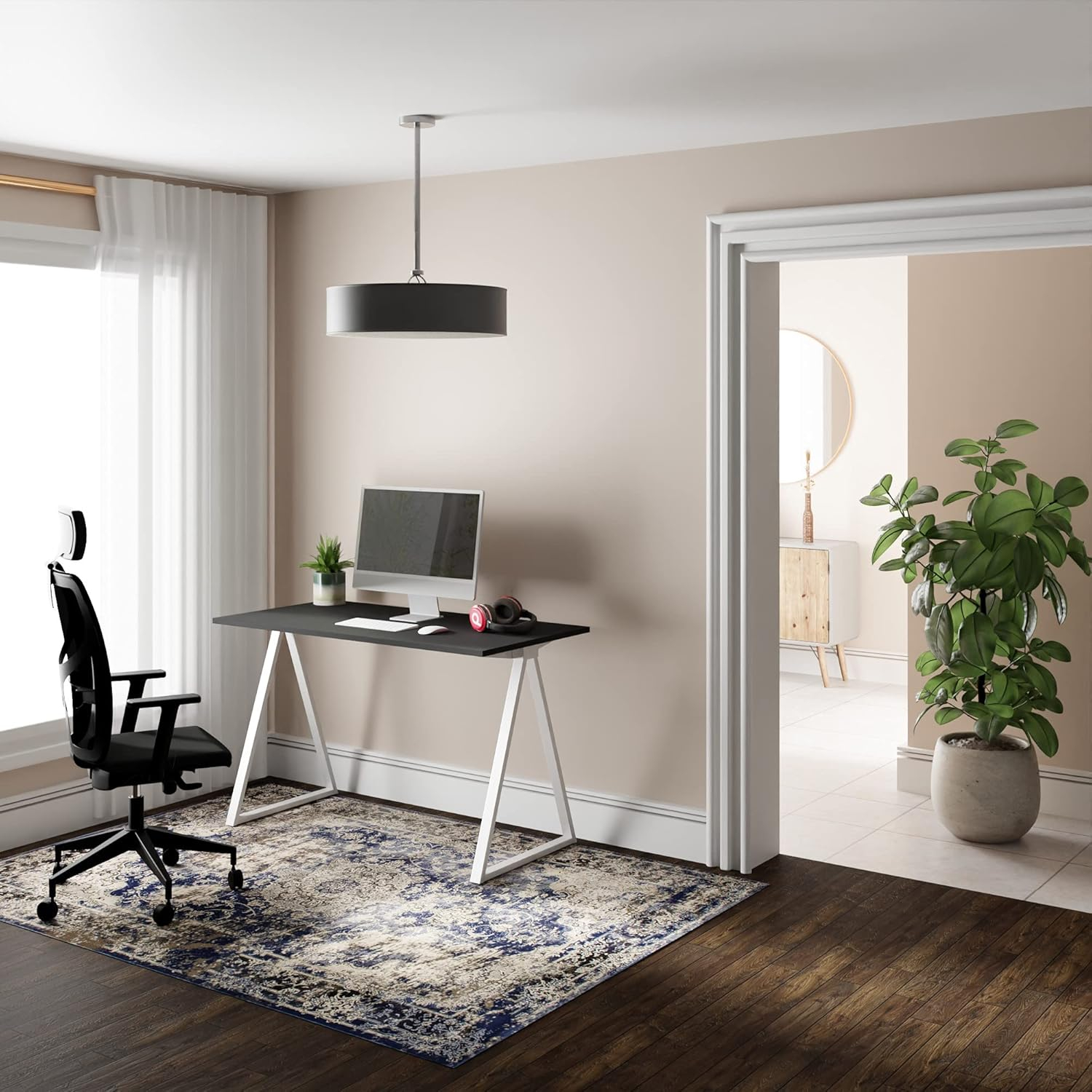 Una silla de oficina negra junto a un escritorio con monitor y auriculares.