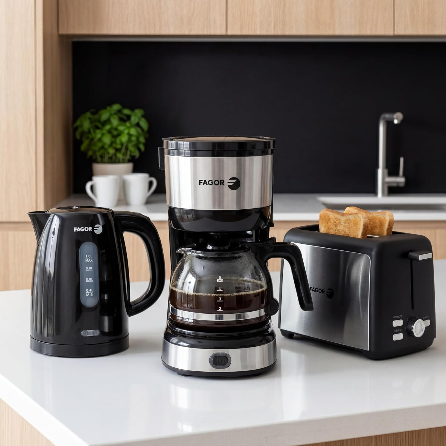 Un hervidor negro, una cafetera con jarra y una tostadora con pan tostado en una encimera.