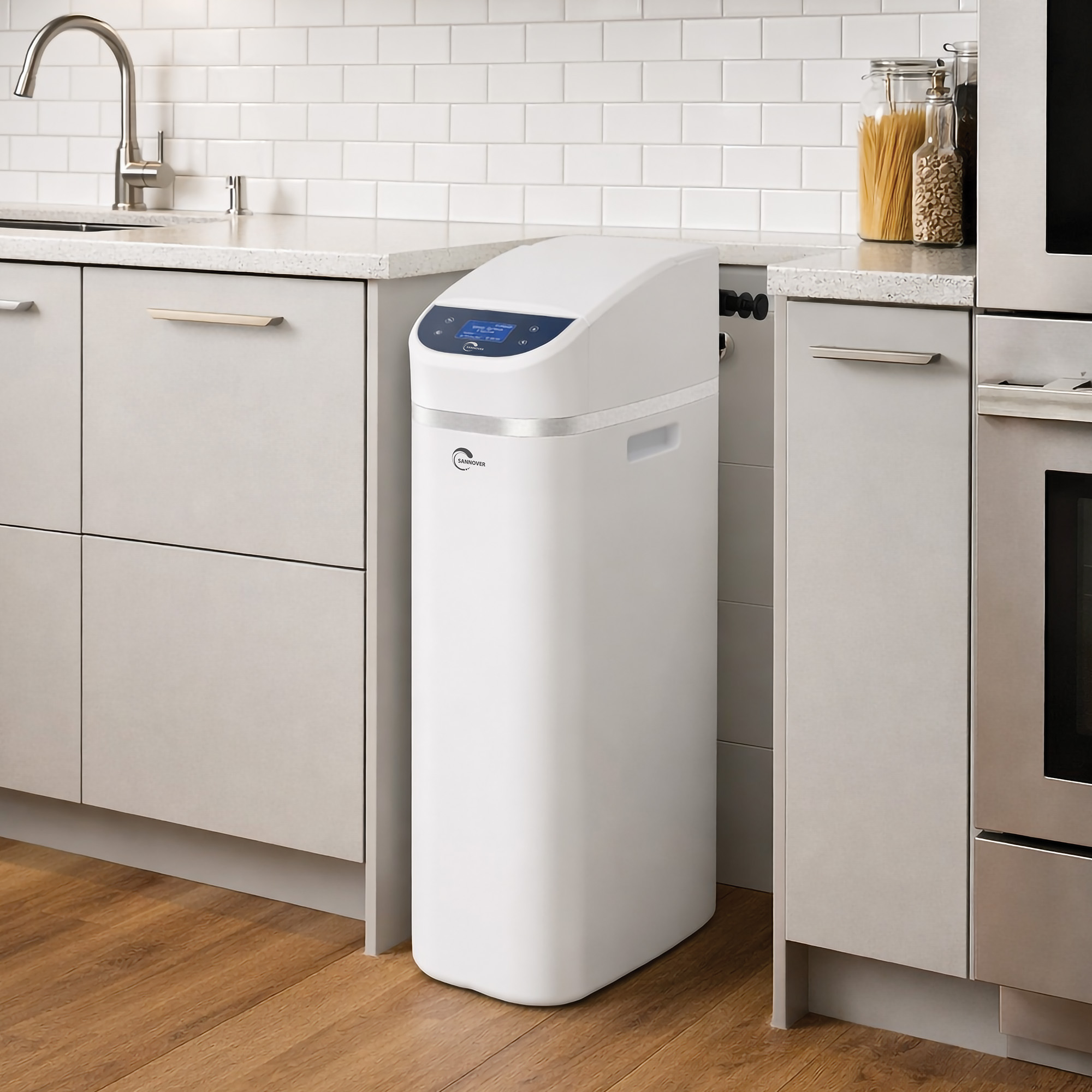 Un descalcificador de agua blanco se encuentra en una cocina moderna junto a armarios y un horno.