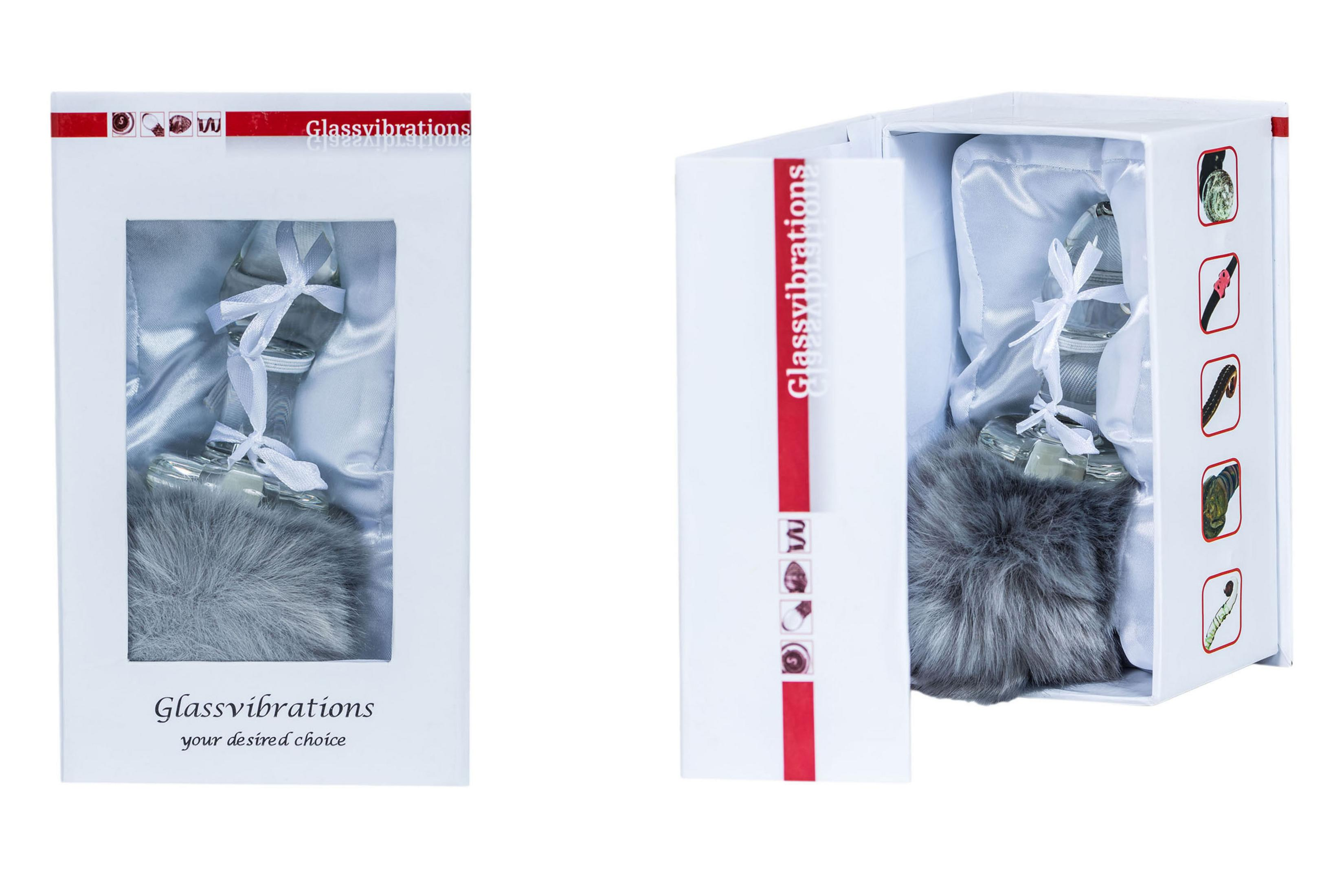 Ein Glasobjekt mit einem grauen Pelzanhänger in einer weißen Geschenkbox.
