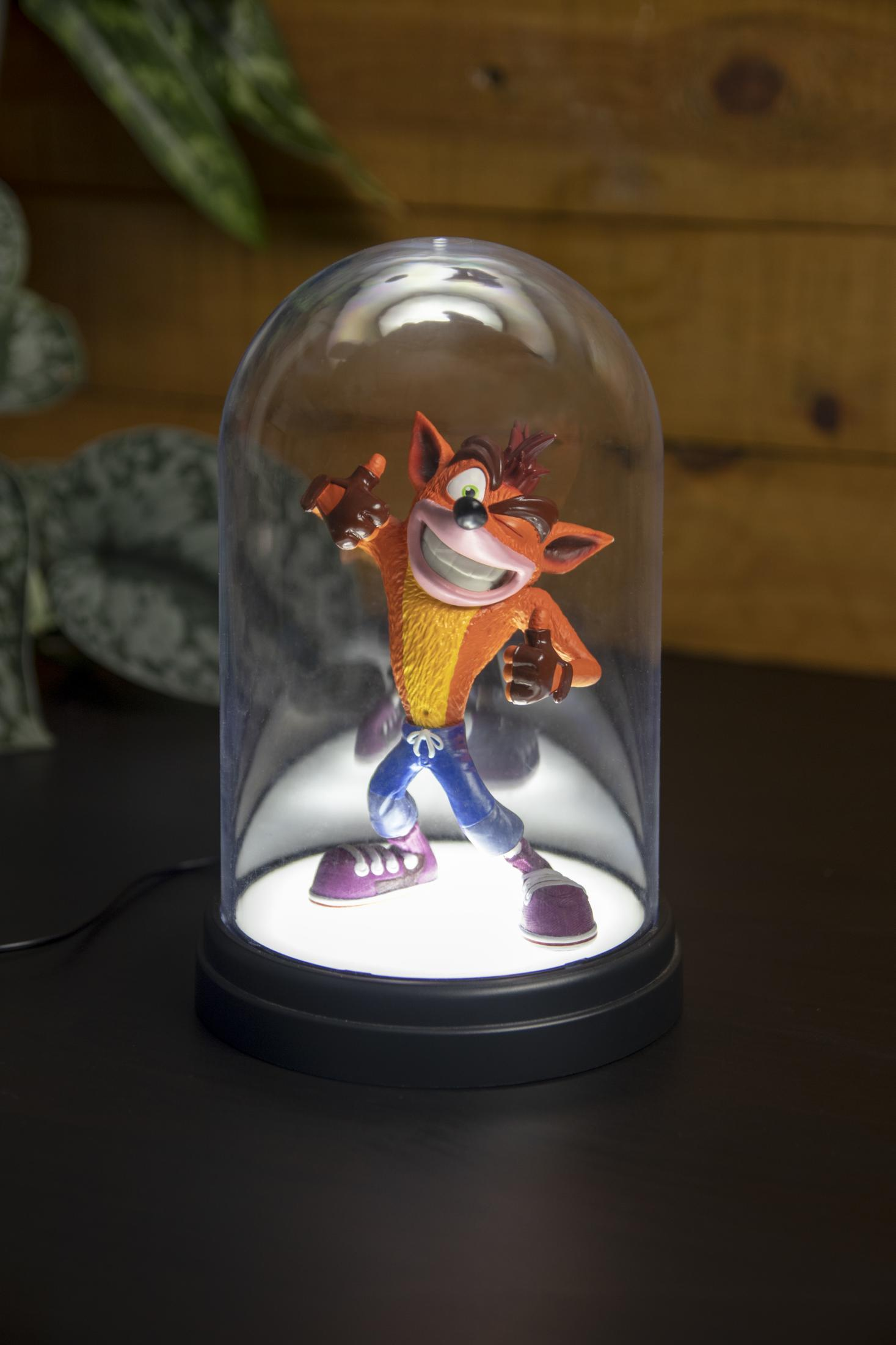 Crash Bandicoot Figur in einer beleuchteten Glaskuppel auf einem dunklen Tisch.