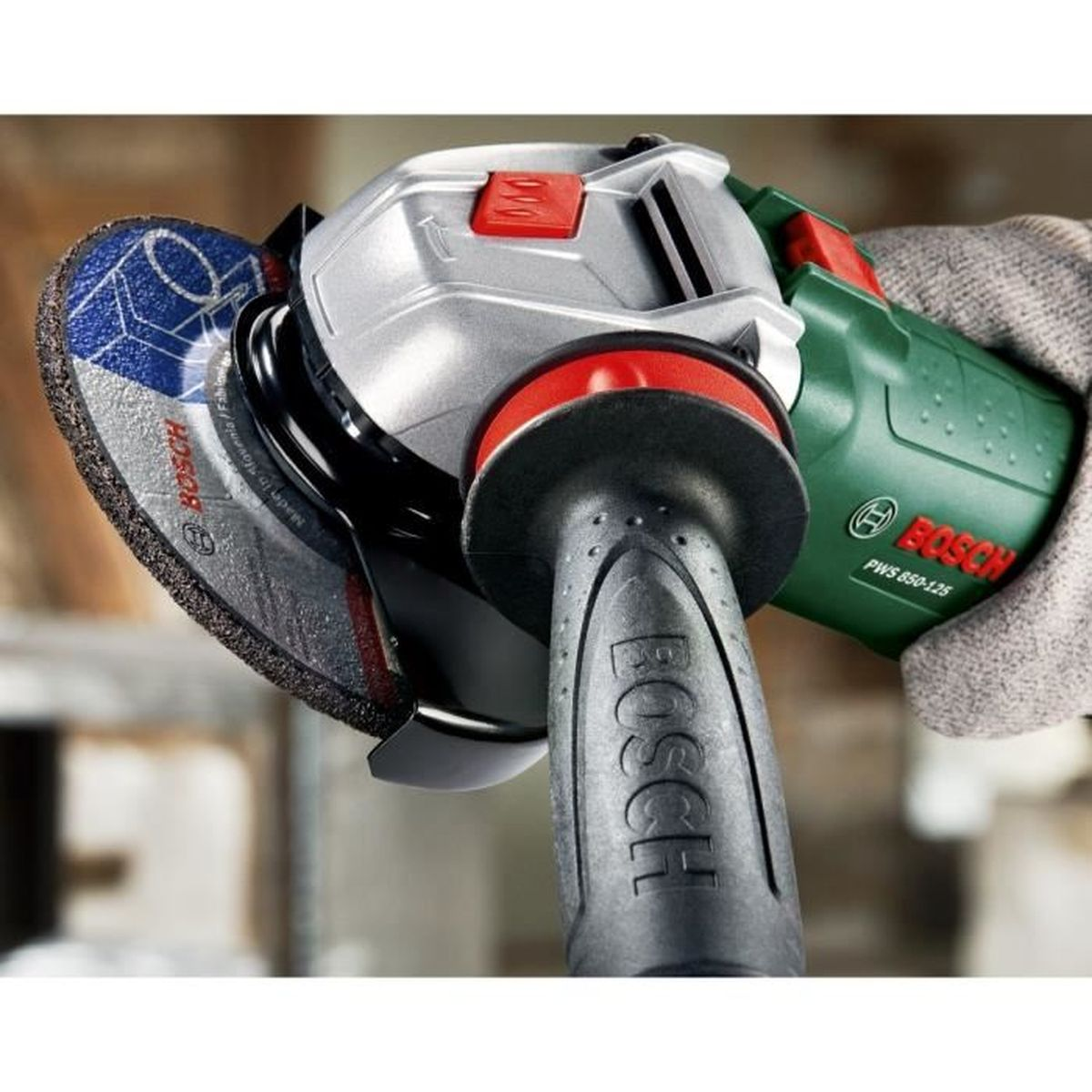 Eine Hand in einem grauen Handschuh hält einen grünen und silbernen Winkelschleifer.