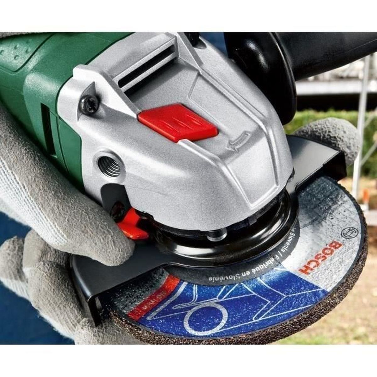 Eine Hand mit Handschuh hält einen Winkelschleifer mit Bosch-Scheibe.