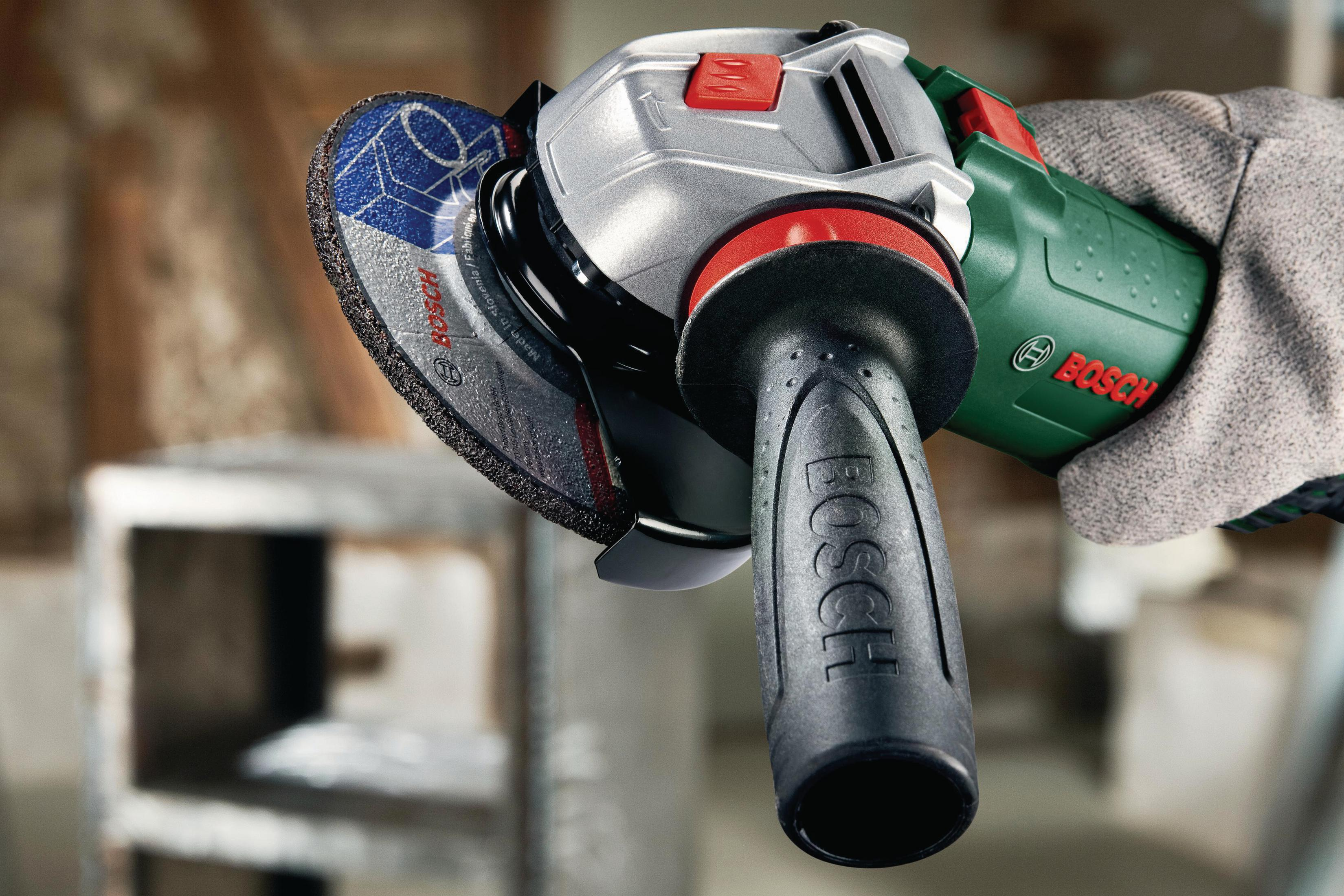 Ein Bosch Winkelschleifer mit blau-silberner Trennscheibe, gehalten von einer Hand mit Handschuh.