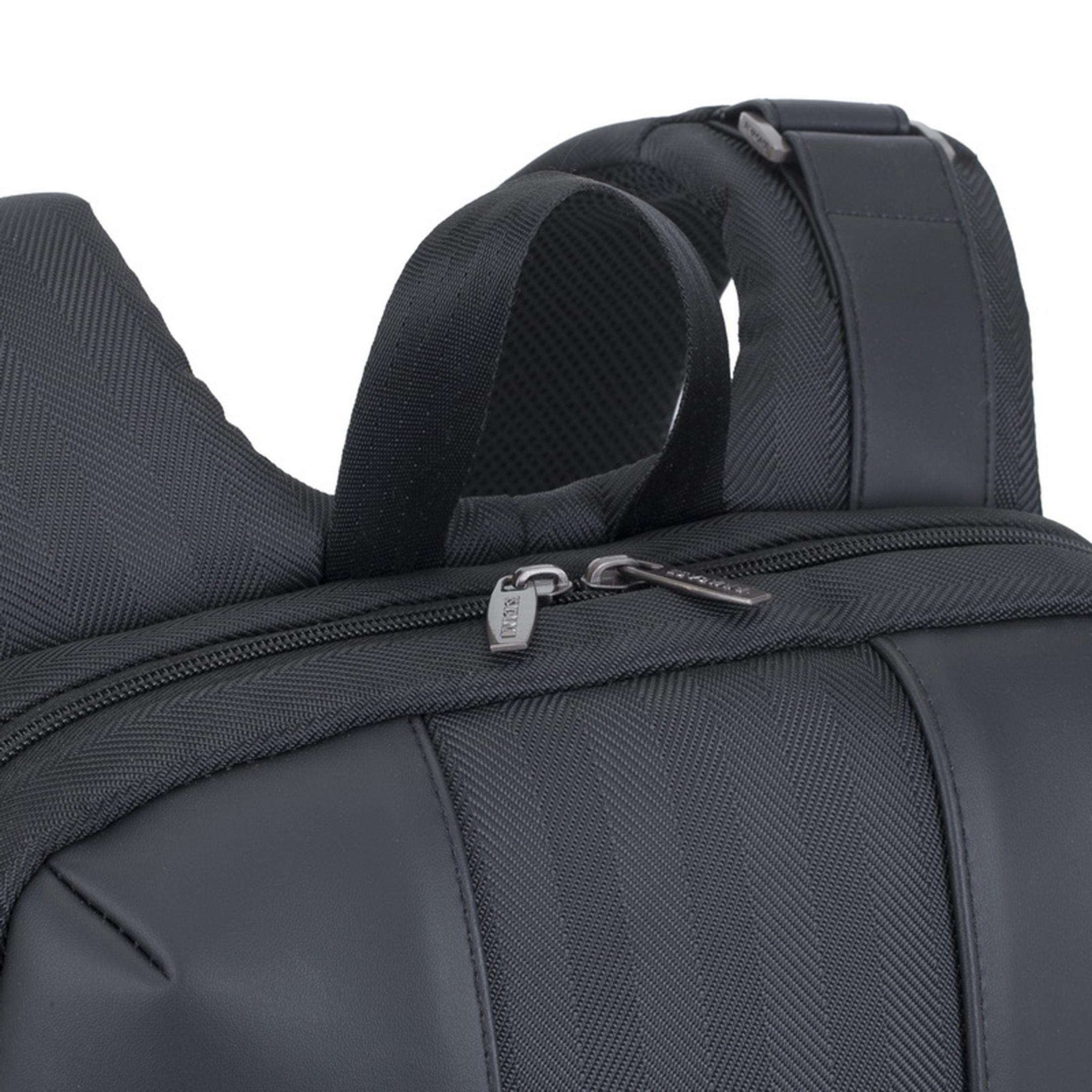 Nahaufnahme einer schwarzen Rucksackklappe mit Reißverschluss und Schultergurt.