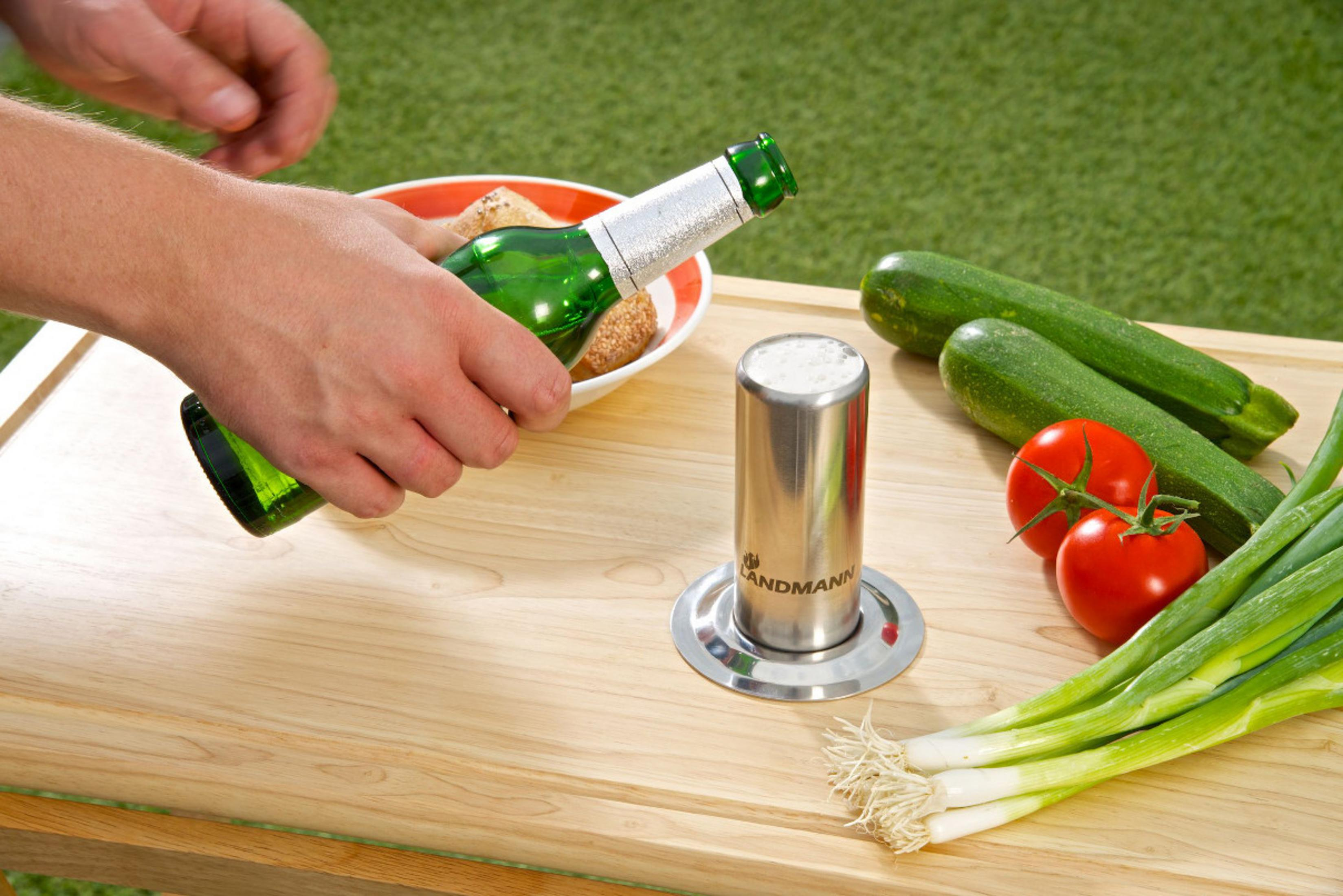 Grüne Flasche wird aus Schüssel genommen, daneben Zucchini, Tomaten und Frühlingszwiebeln.